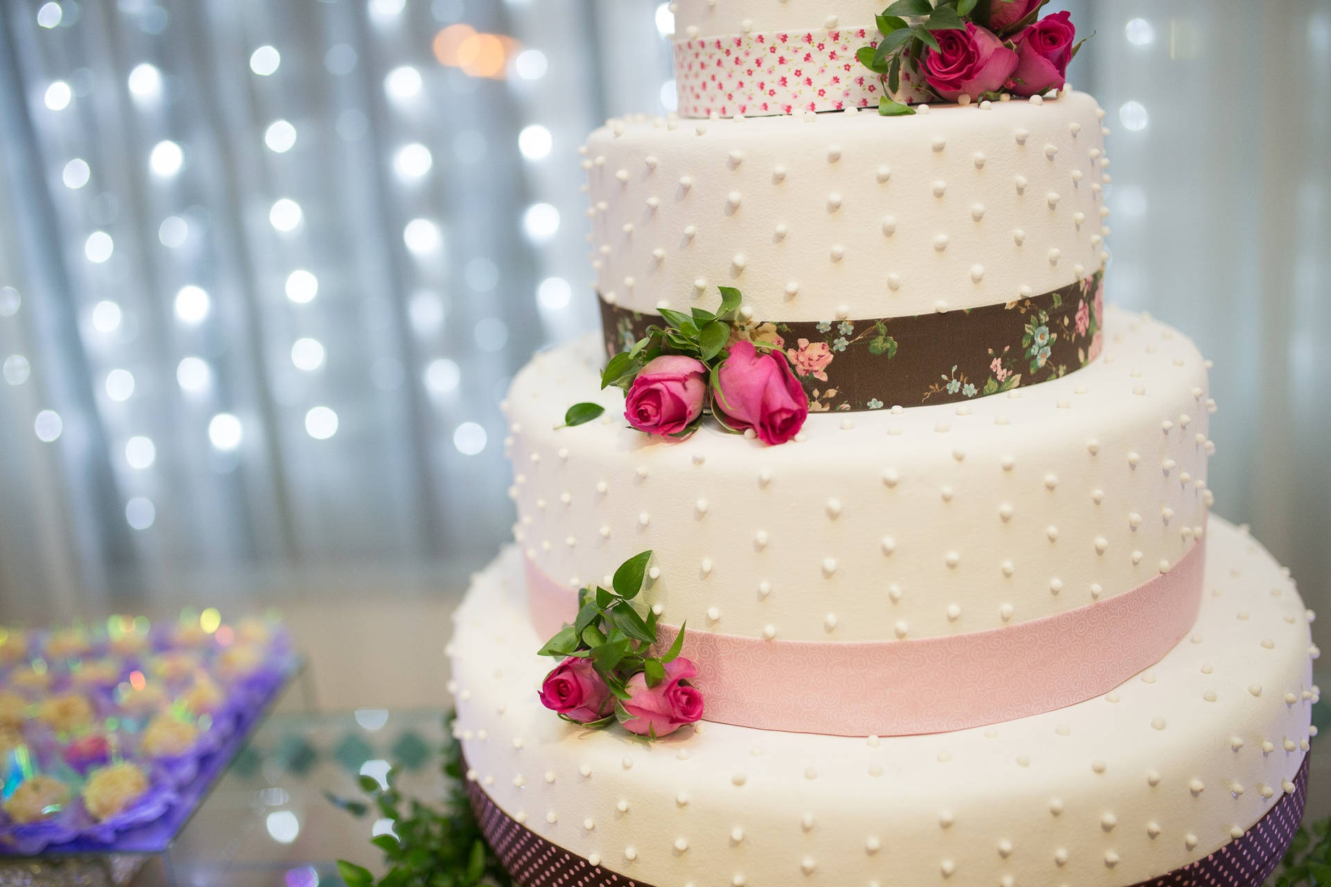 Elegant Tiered Wedding Cake Embellished With Pearls, Roses And Ribbons