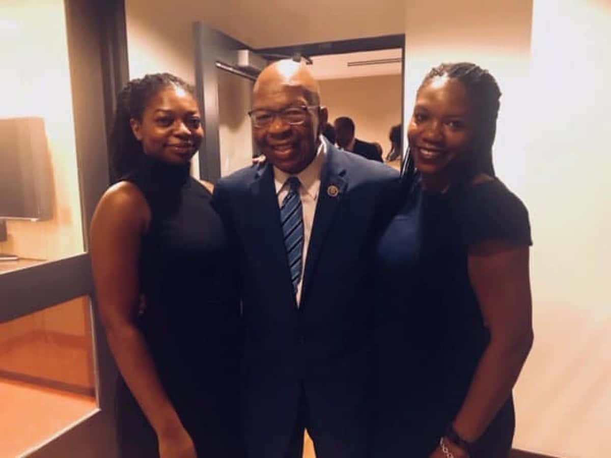 Elijah Cummings Smiling And Posing With Women Background