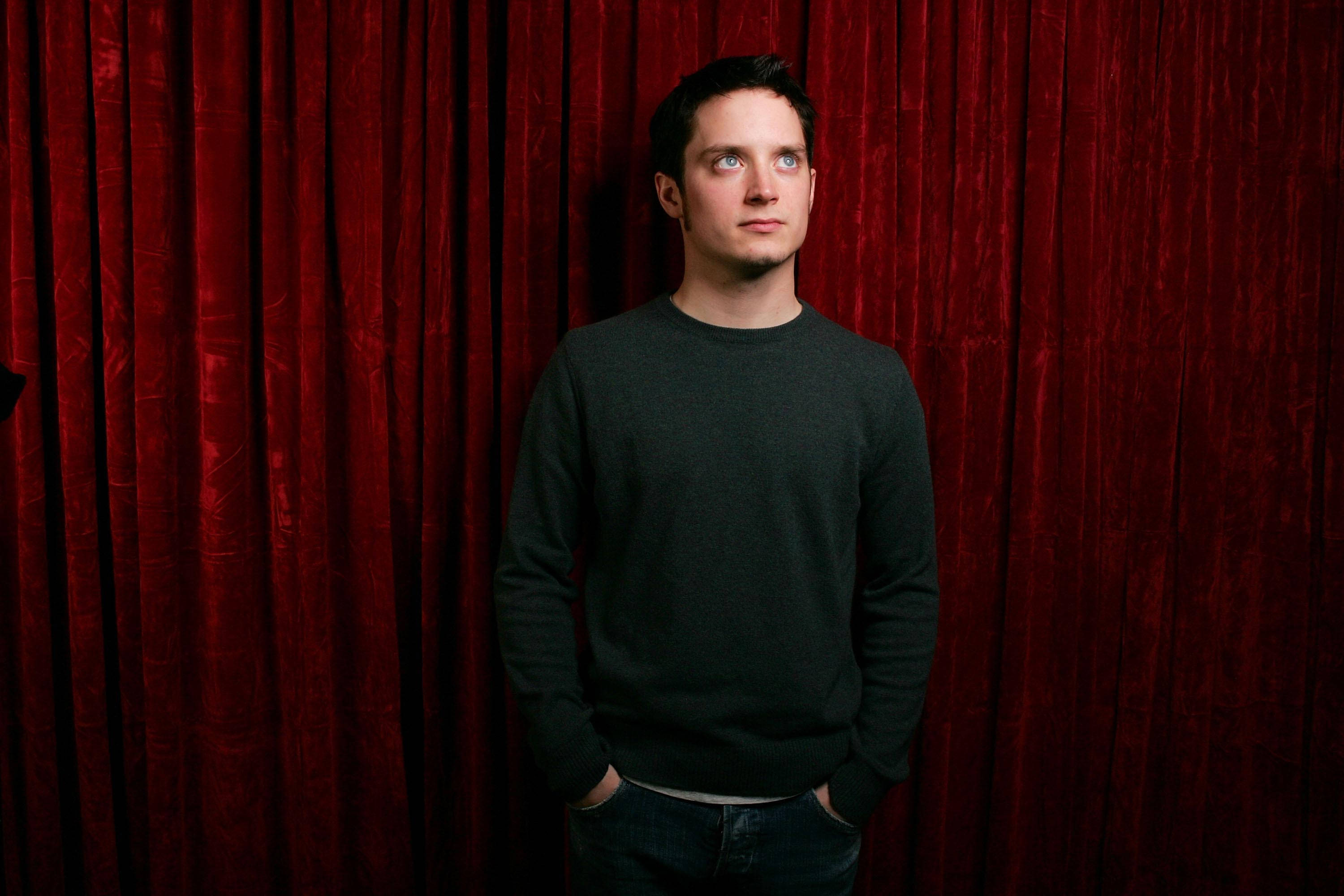 Elijah Wood In Front Of Red Curtain Background