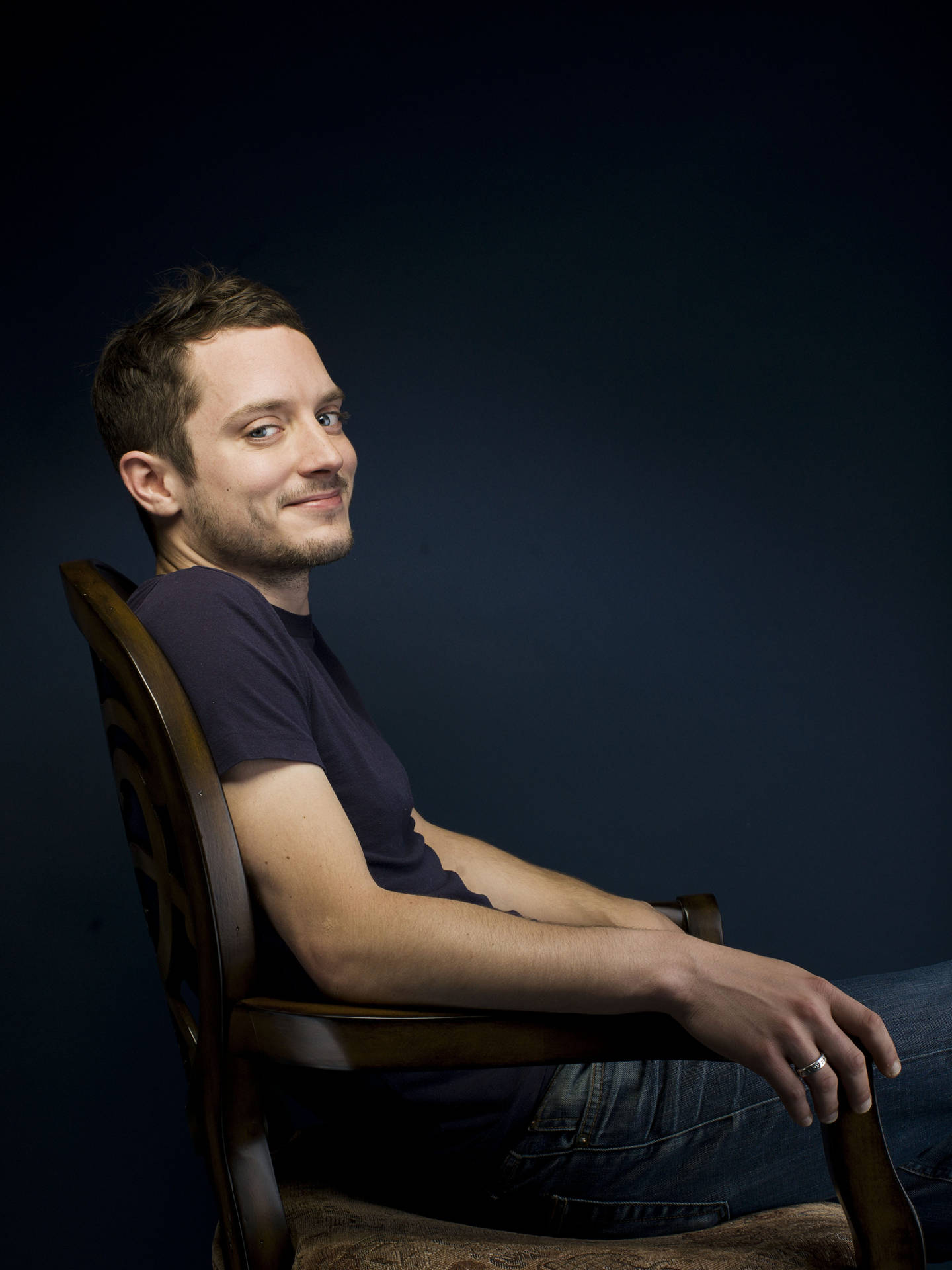 Elijah Wood Seated On A Chair Background