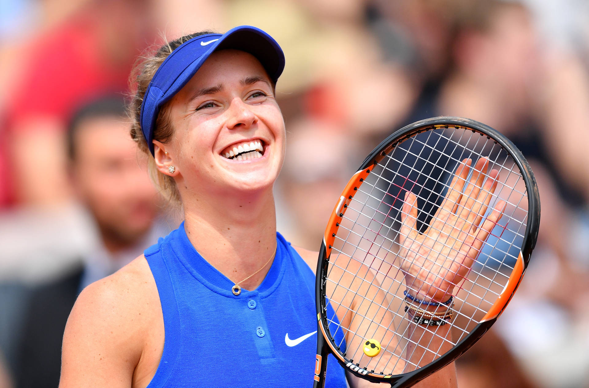 Elina Svitolina Holding A Tennis Racket With A Smile Background