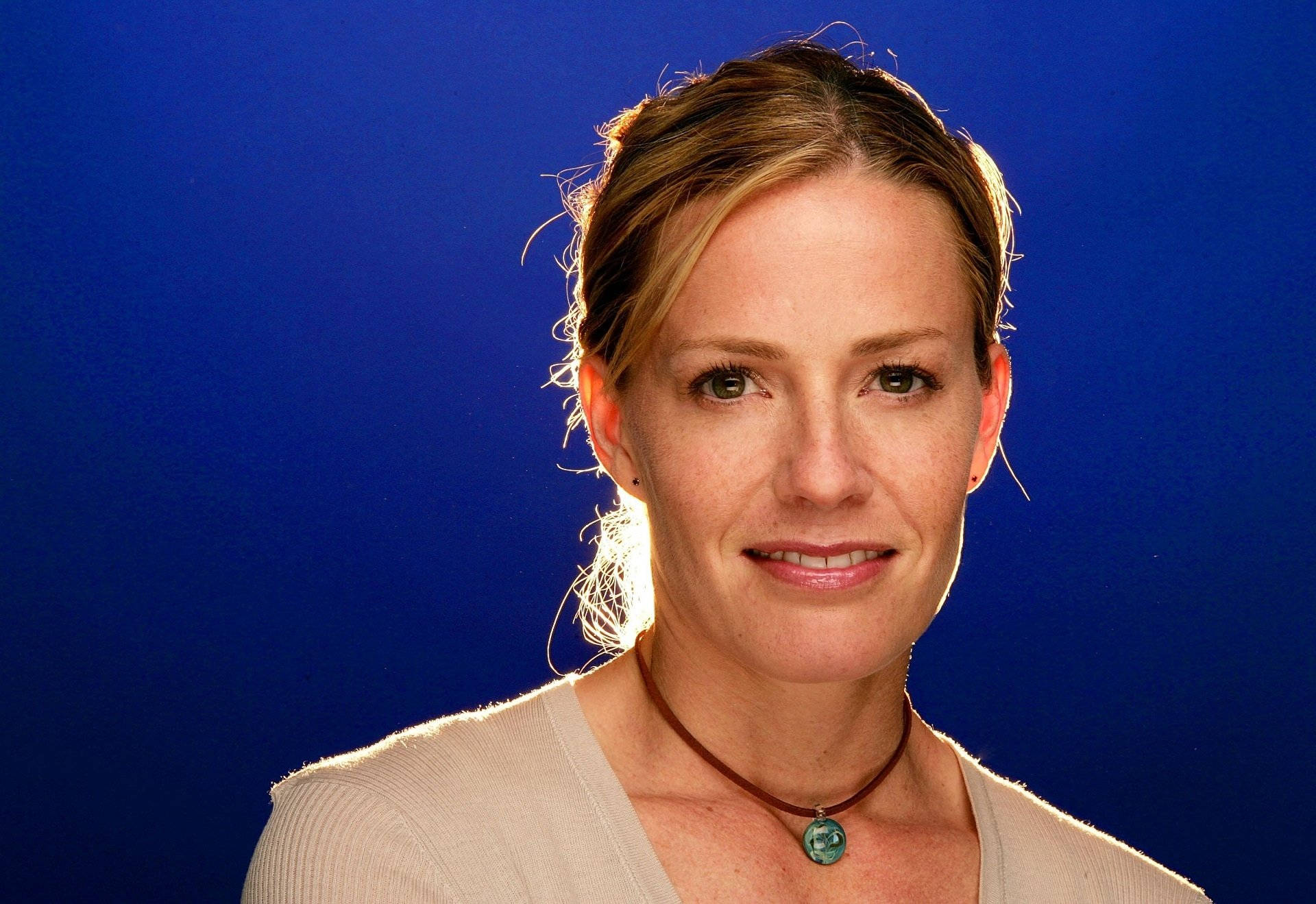 Elisabeth Shue Smiling With Hair Tied In Front Of Royal Blue Background Background