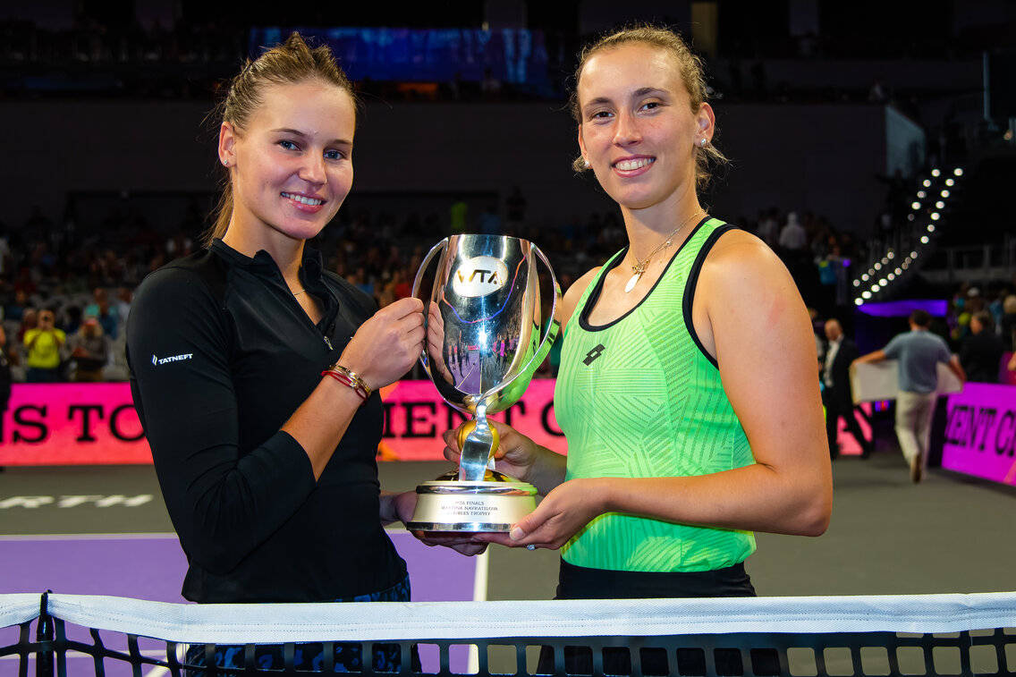 Elise Mertens And Veronika Kudermetova In Action On The Tennis Court Background