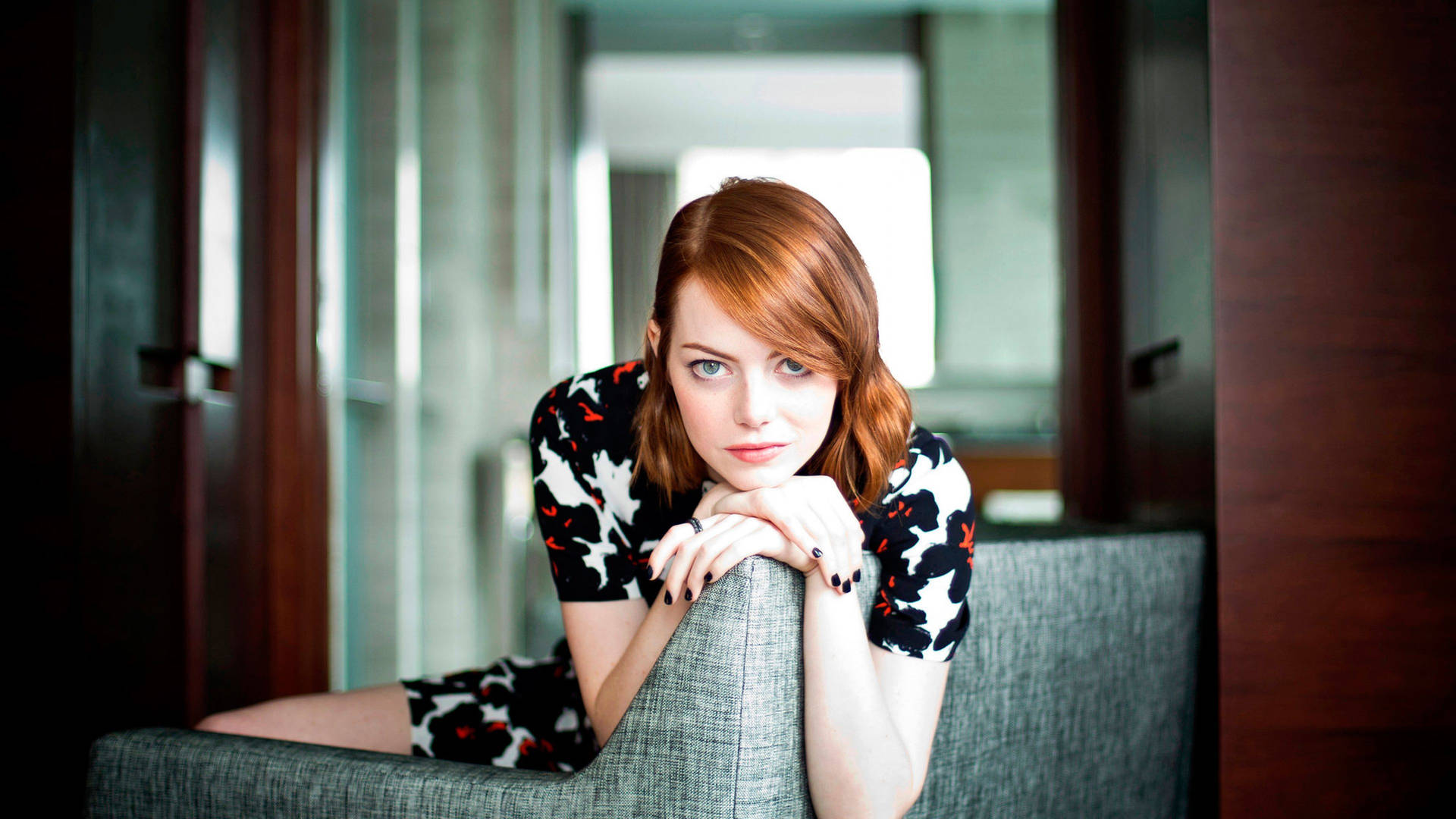 Emma Stone Perched On A Large Couch Background