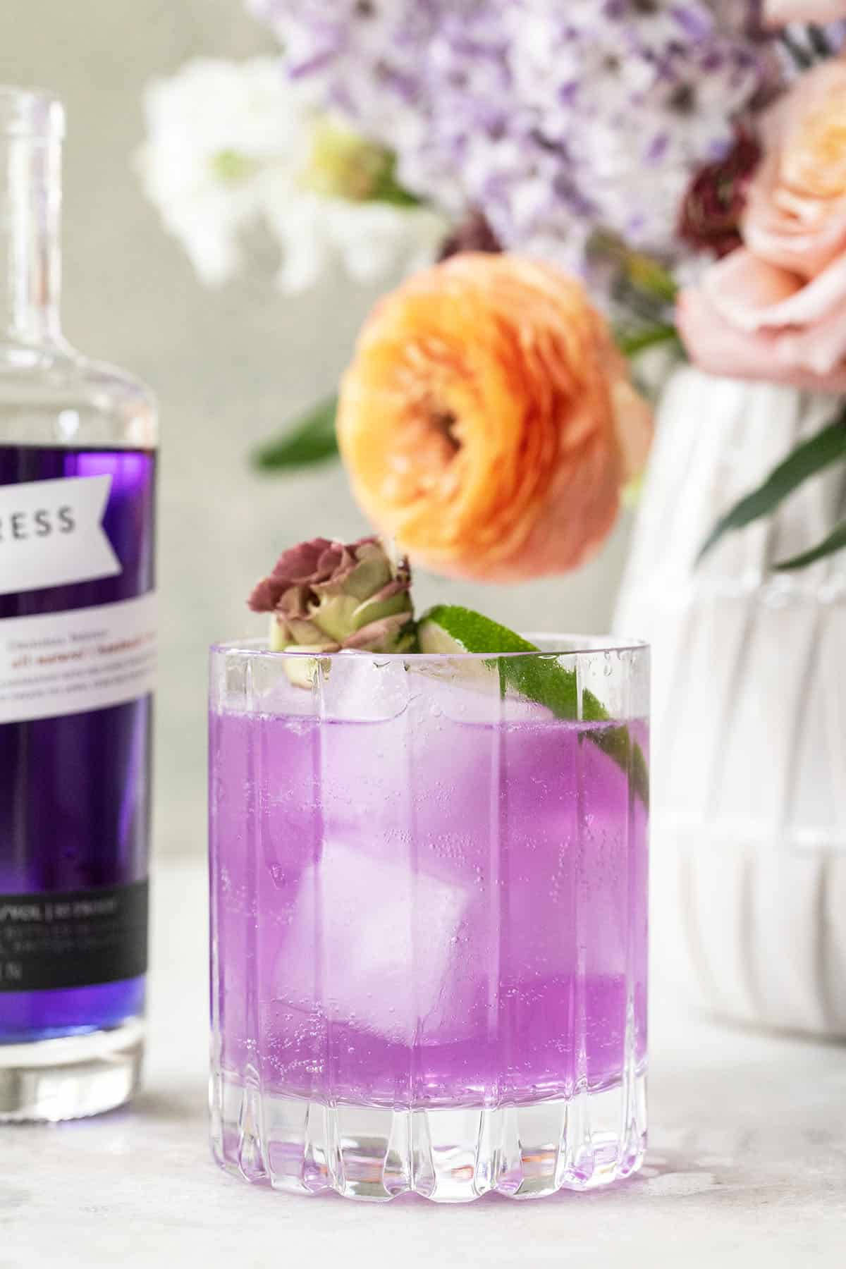 Empress Gin On Rocks Glass With Flowers Background