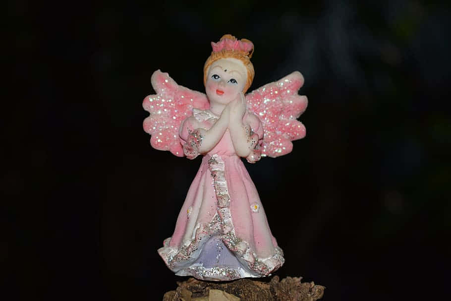 Endearing Angel Figurine With Delicate Pink Wings Background