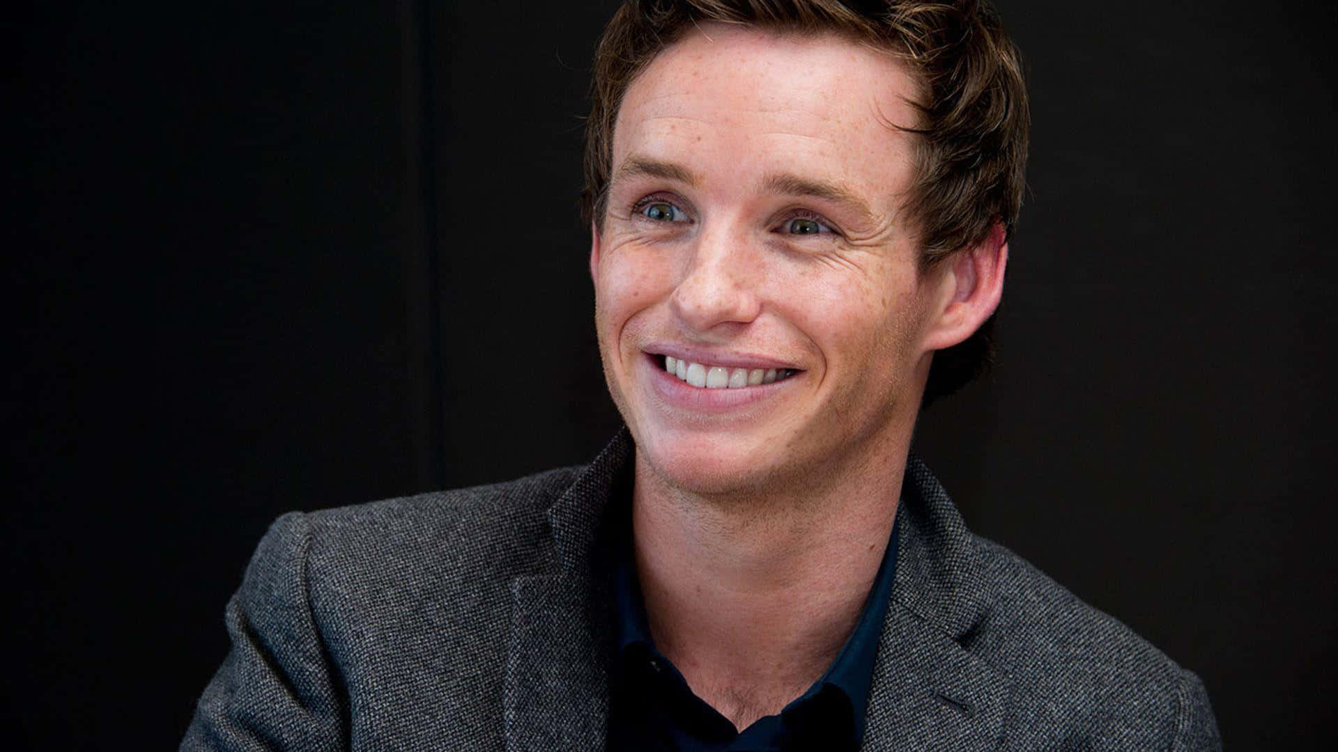 English Actor Eddie Redmayne Posing In A Stylish Suit Background