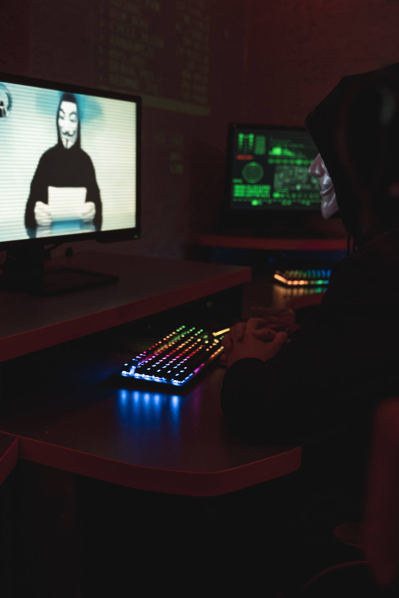 Enigmatic Cybersecurity: Man In Hacker Mask On Television Background