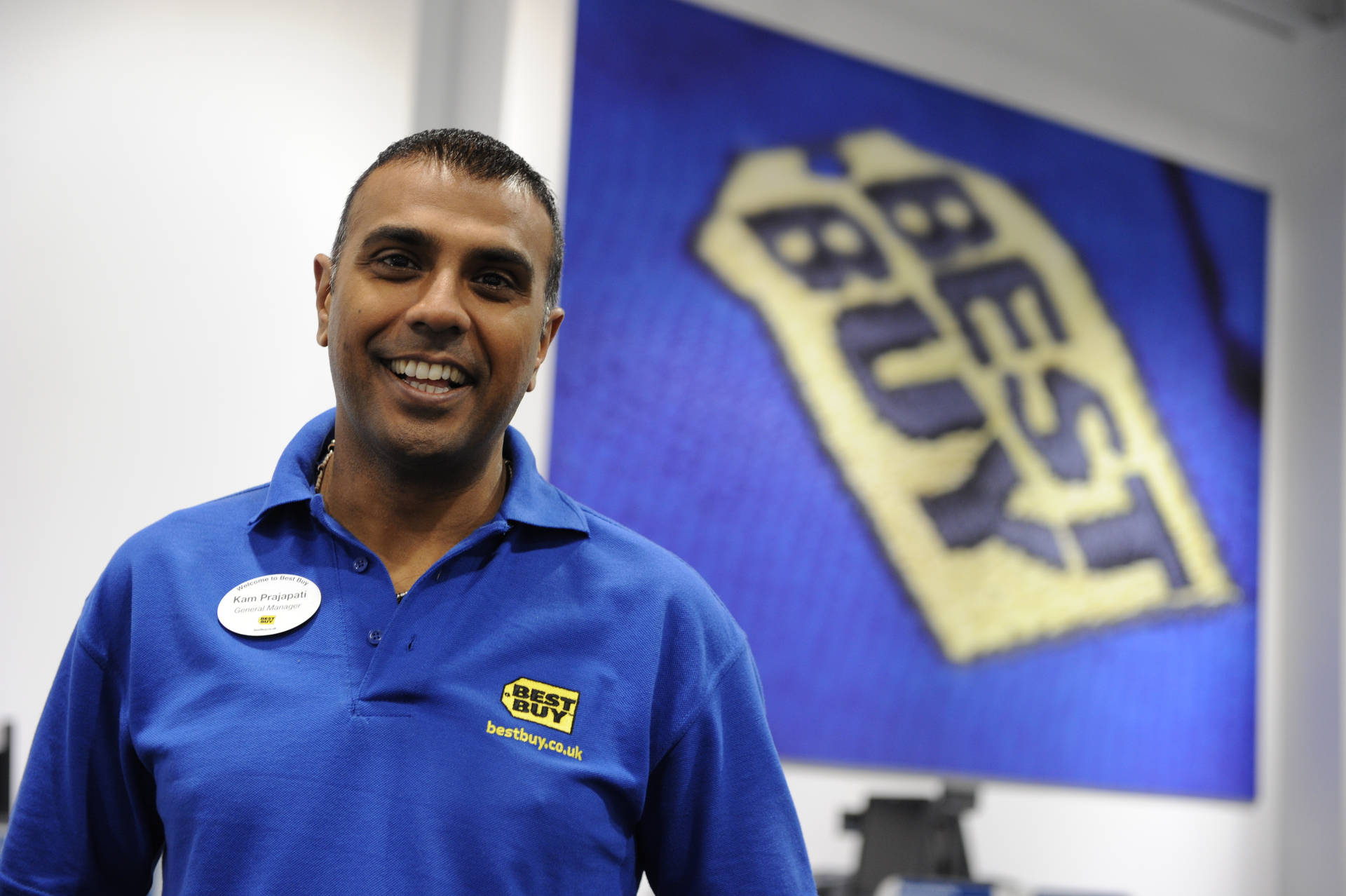 Enthusiastic Best Buy Employee Ready To Assist Customers Background