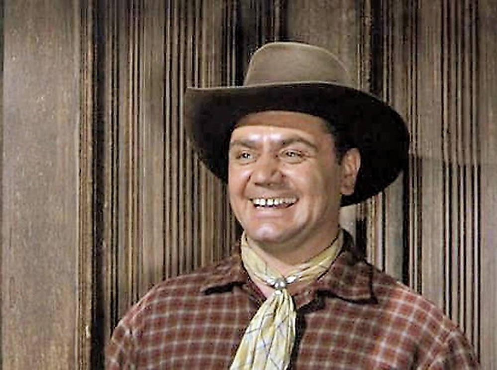 Ernest Borgnine Smiling In A Brown Plaid Shirt Background