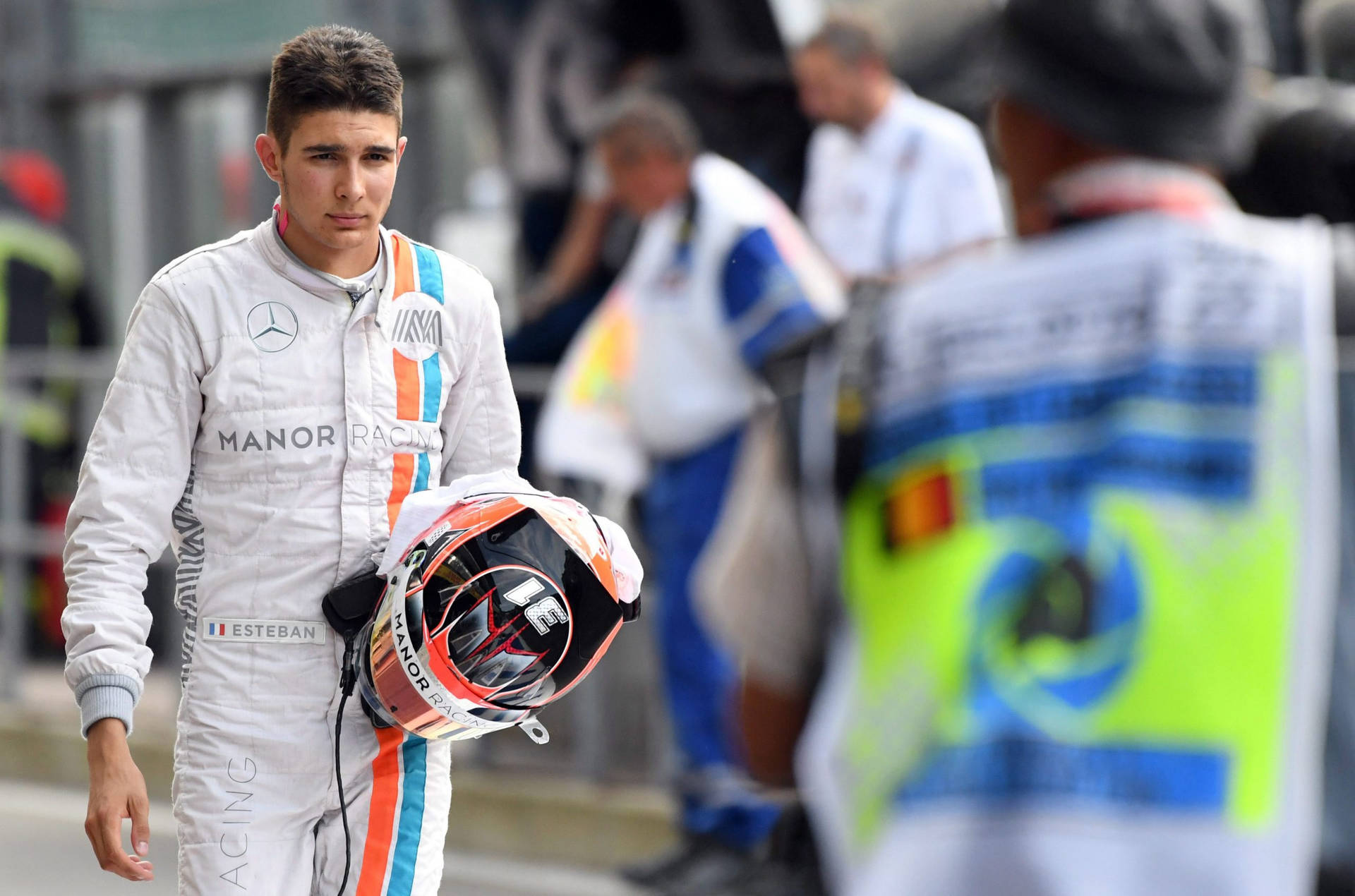 Esteban Ocon Holding His Racing Helmet During A Racing Event Background