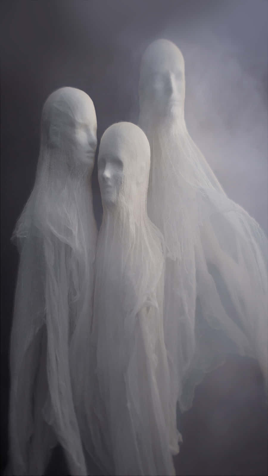 Ethereal Ghostly Figures Shroudedin Mist Background