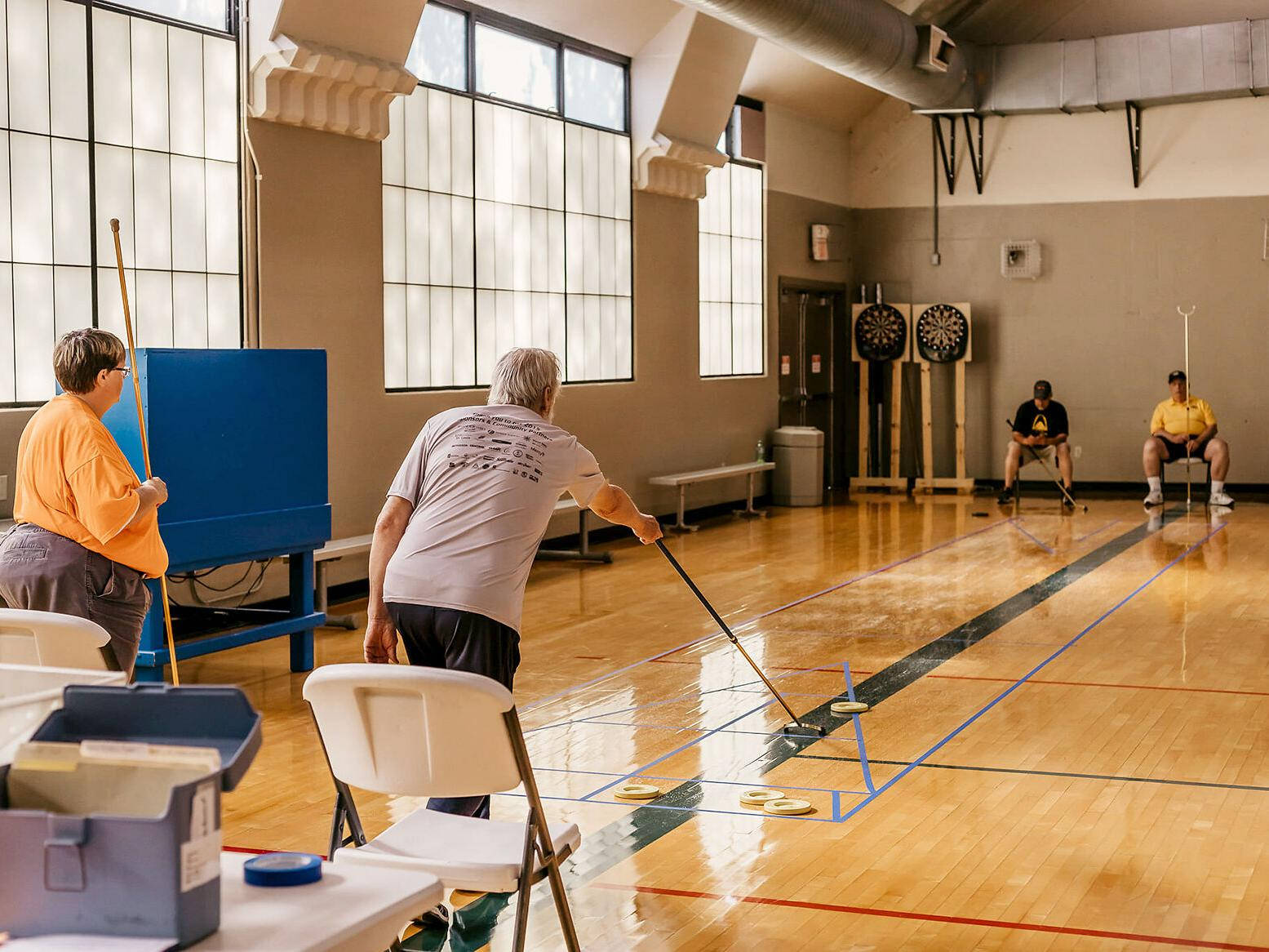 Excitement On The Court: A Game Of Indoor Floor Shuffleboard Background