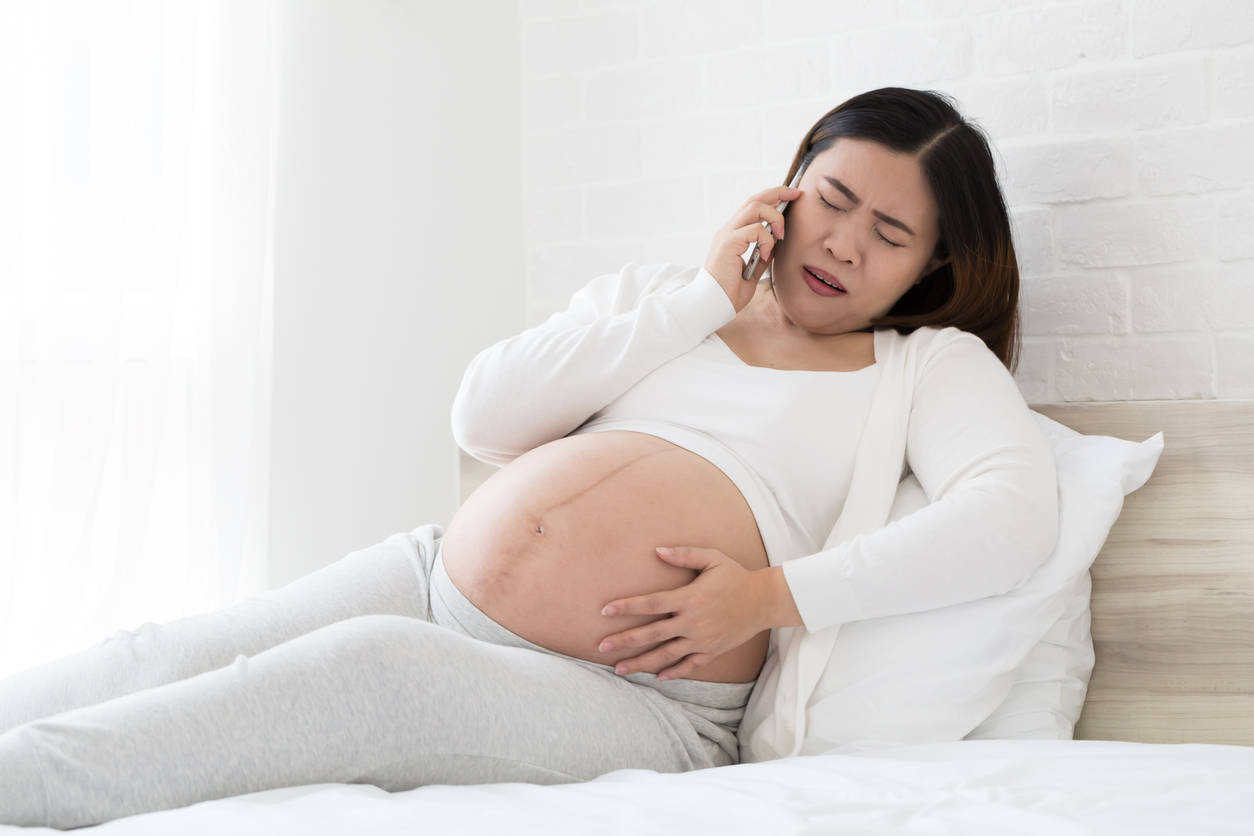 Expectant Mother Experiencing Abdominal Pain During A Phone Call Background