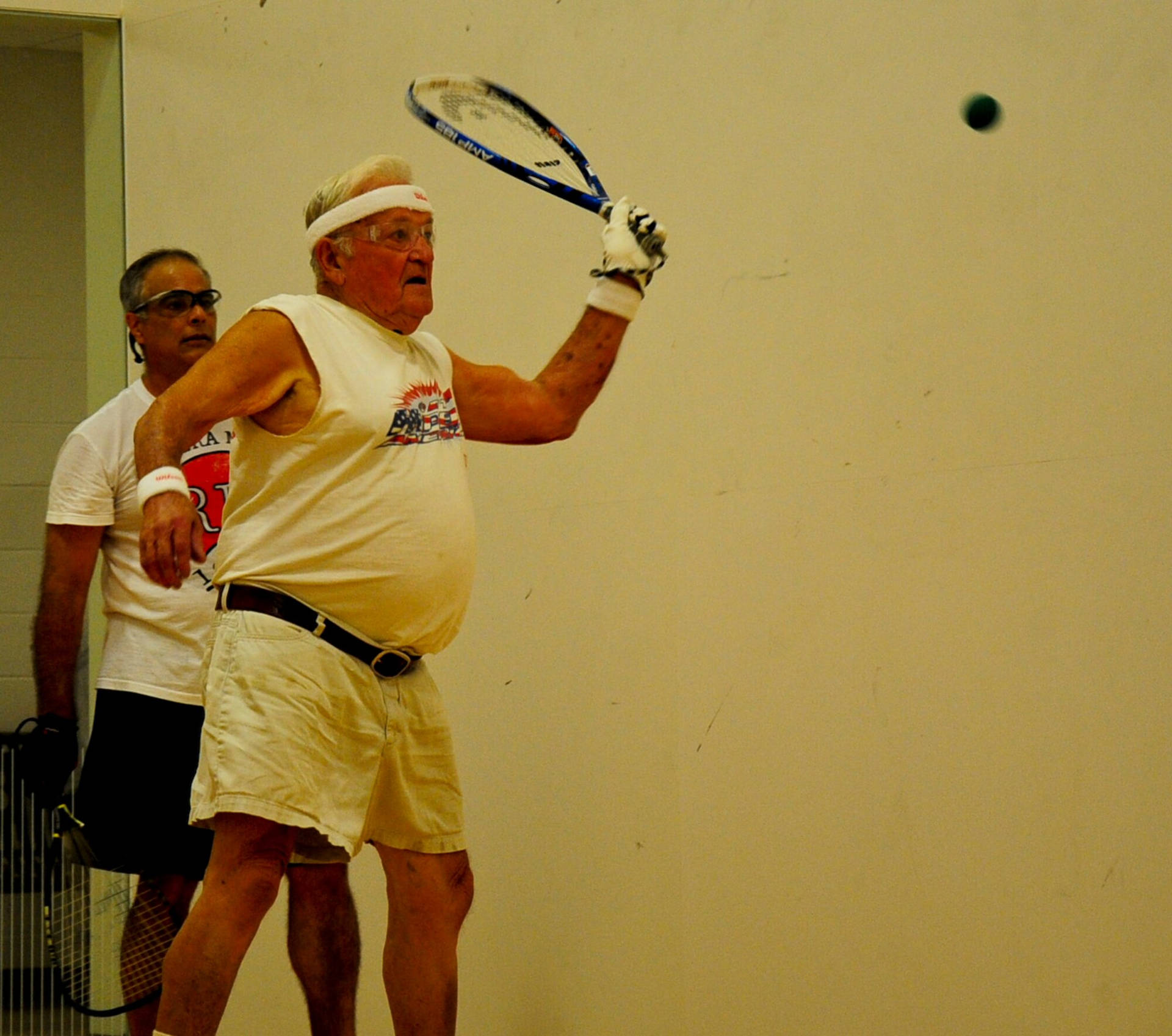 Experienced Senior Playing An Intense Game Of Racquetball Background