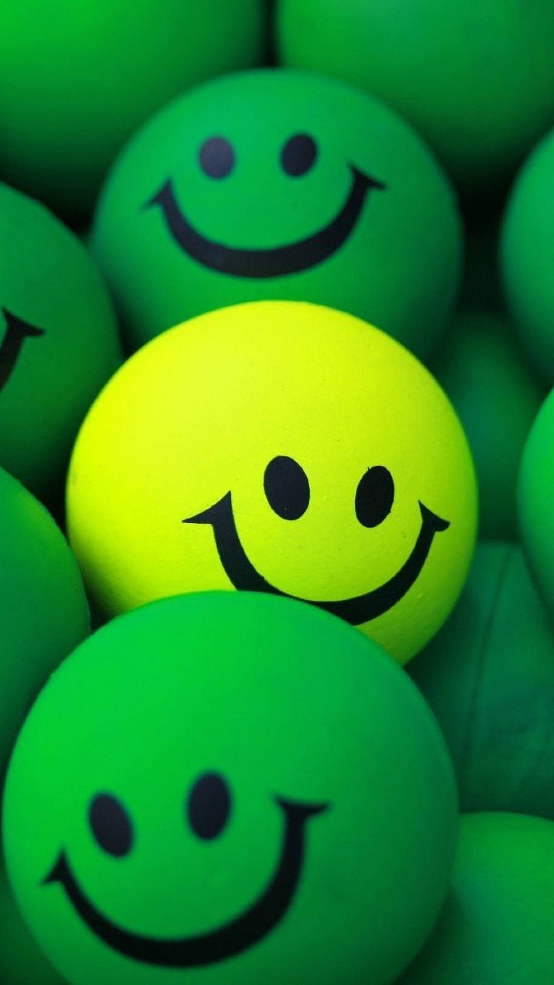 Expressive Yellow Smiley Ball Amongst Green Balls