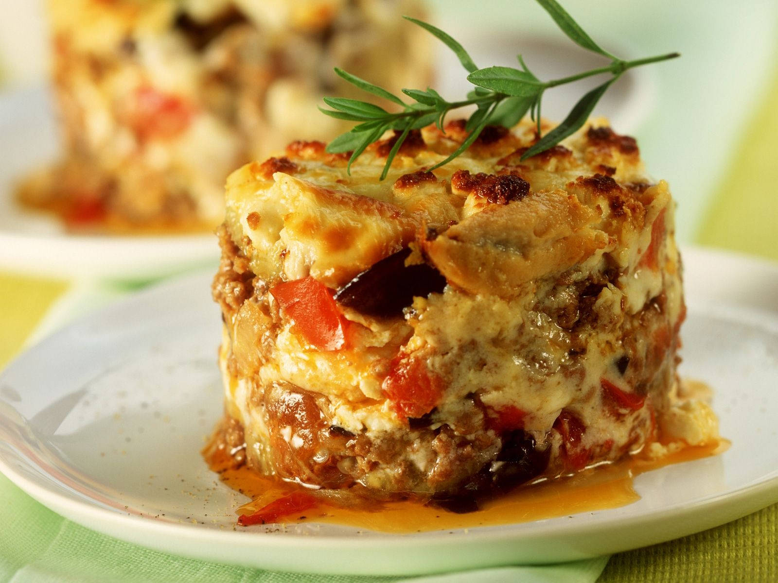 Exquisite Close-up Of Savory Moussaka Garnished With Fresh Rosemary Background