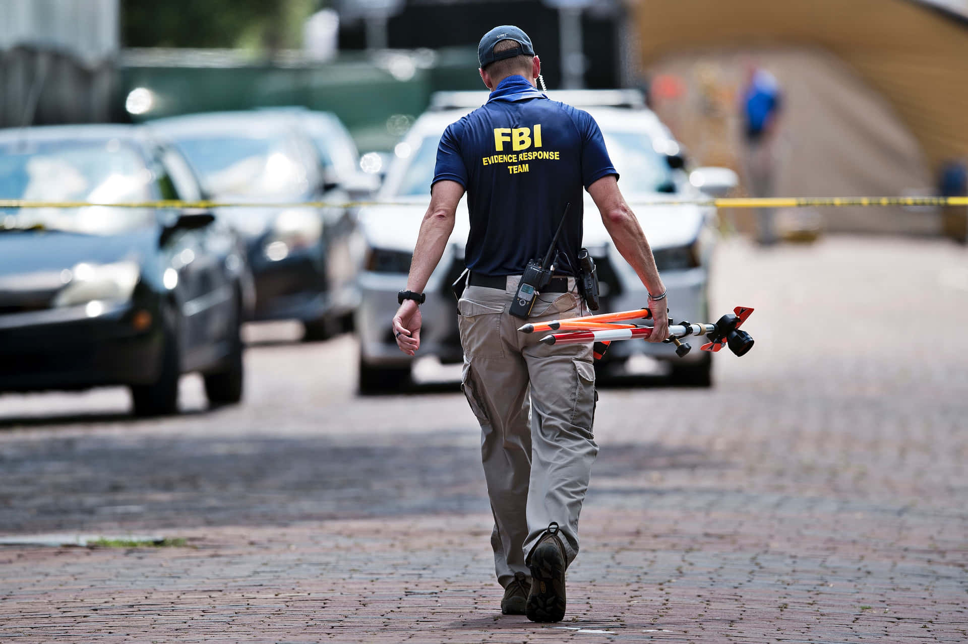 Fbi Agent Walks Down A Street With A Drone Background
