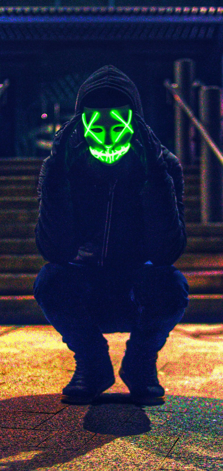 Fear Meets Mystery - A Man In A Chilling Purge Mask Crouched In Darkness