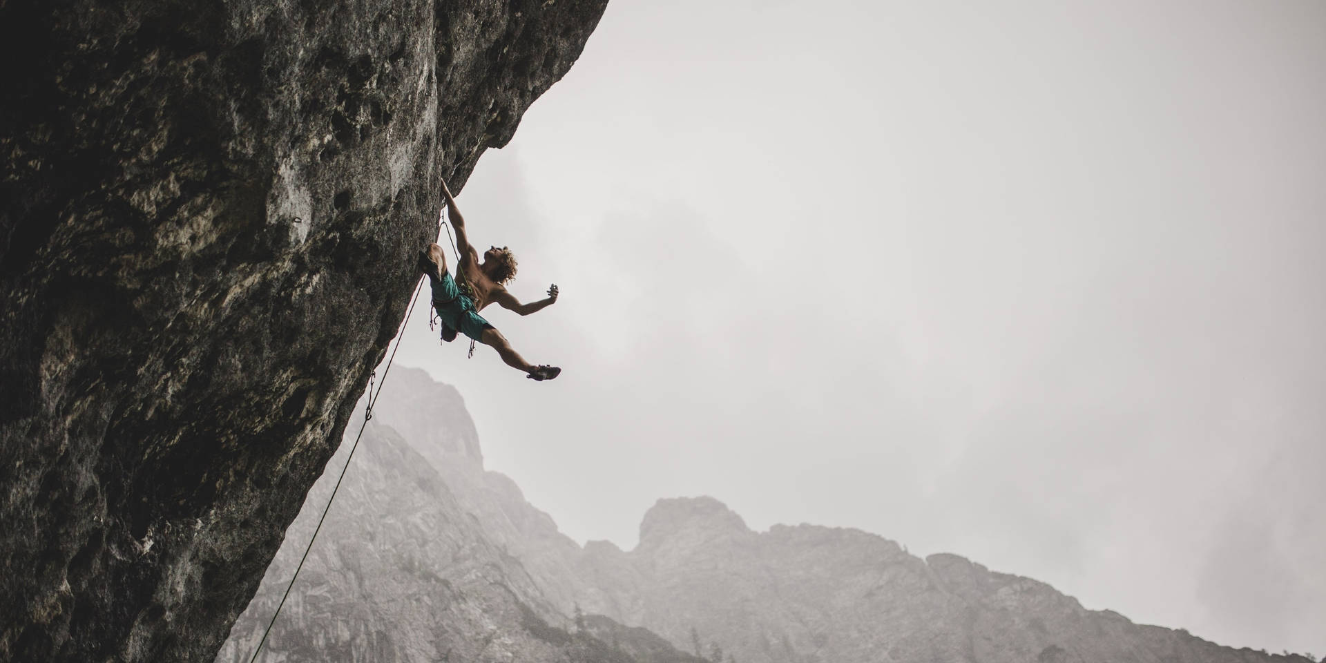 Fearless Adventurer Conquers The Cliff Amidst Stormy Skies Background