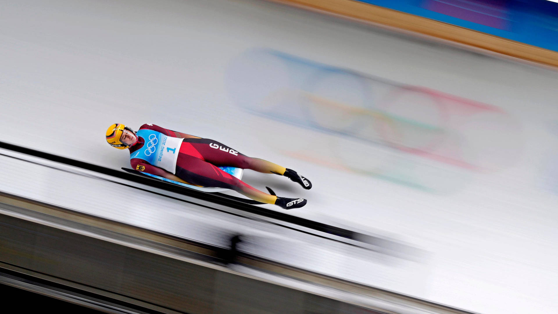 Fearless Luge Athlete In High-speed Action Background