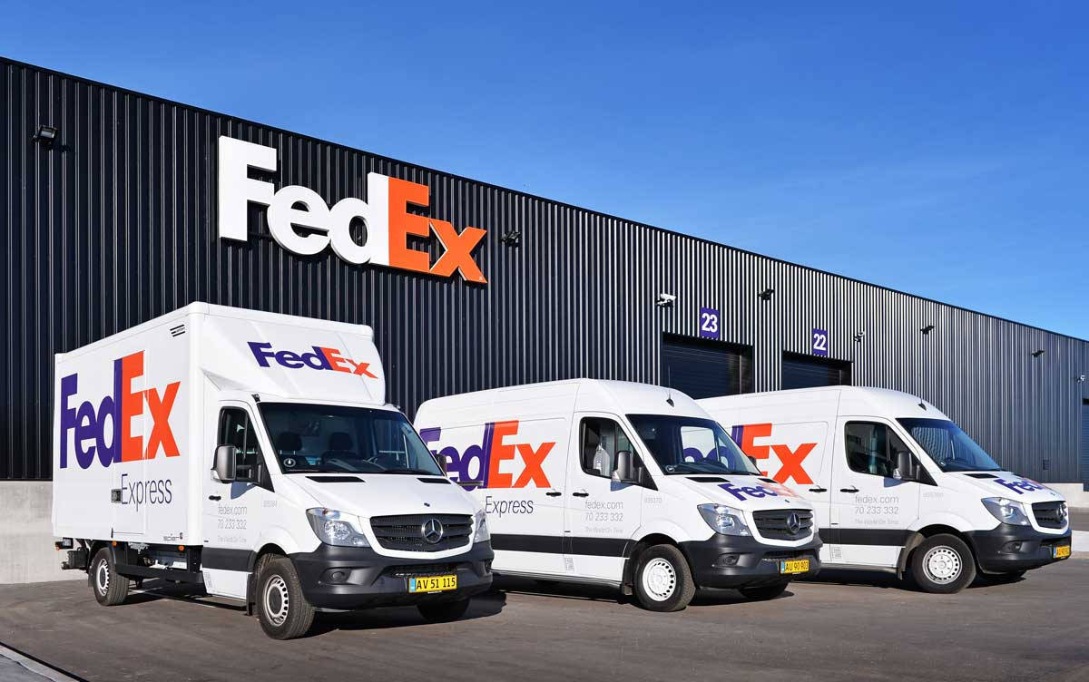 Fedex Tracking Vehicles Near Warehouse Background