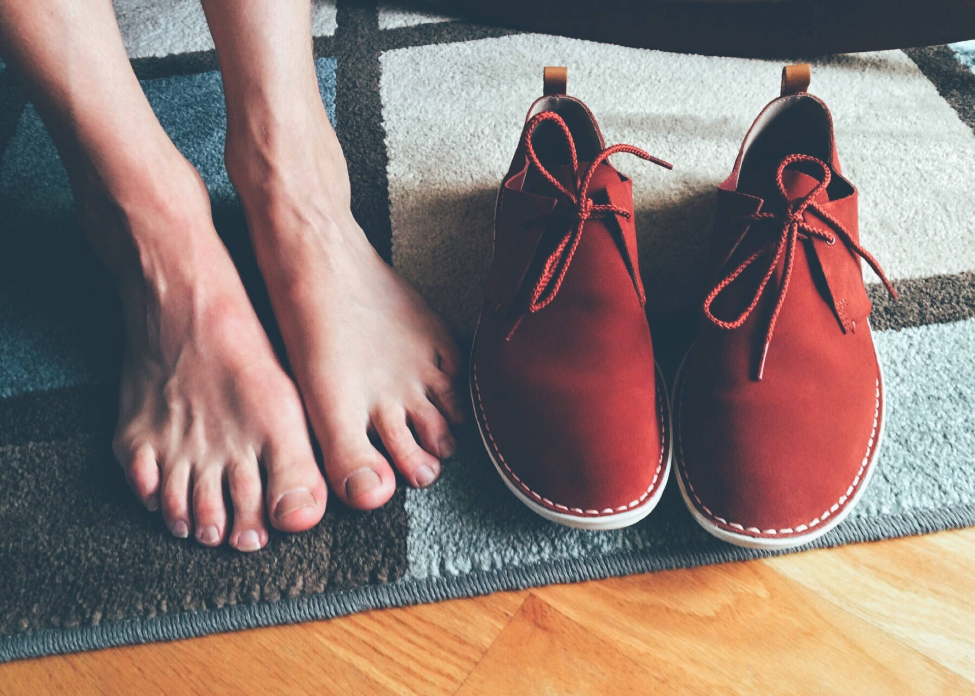 Feet Beside Red Suede Shoes Background