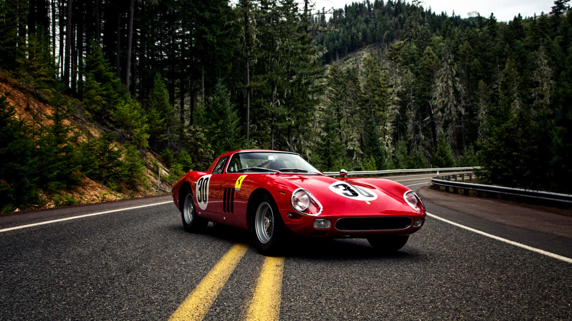 Ferrari F40 - A Classic Sports Car Driving Down A Mountain Road Background