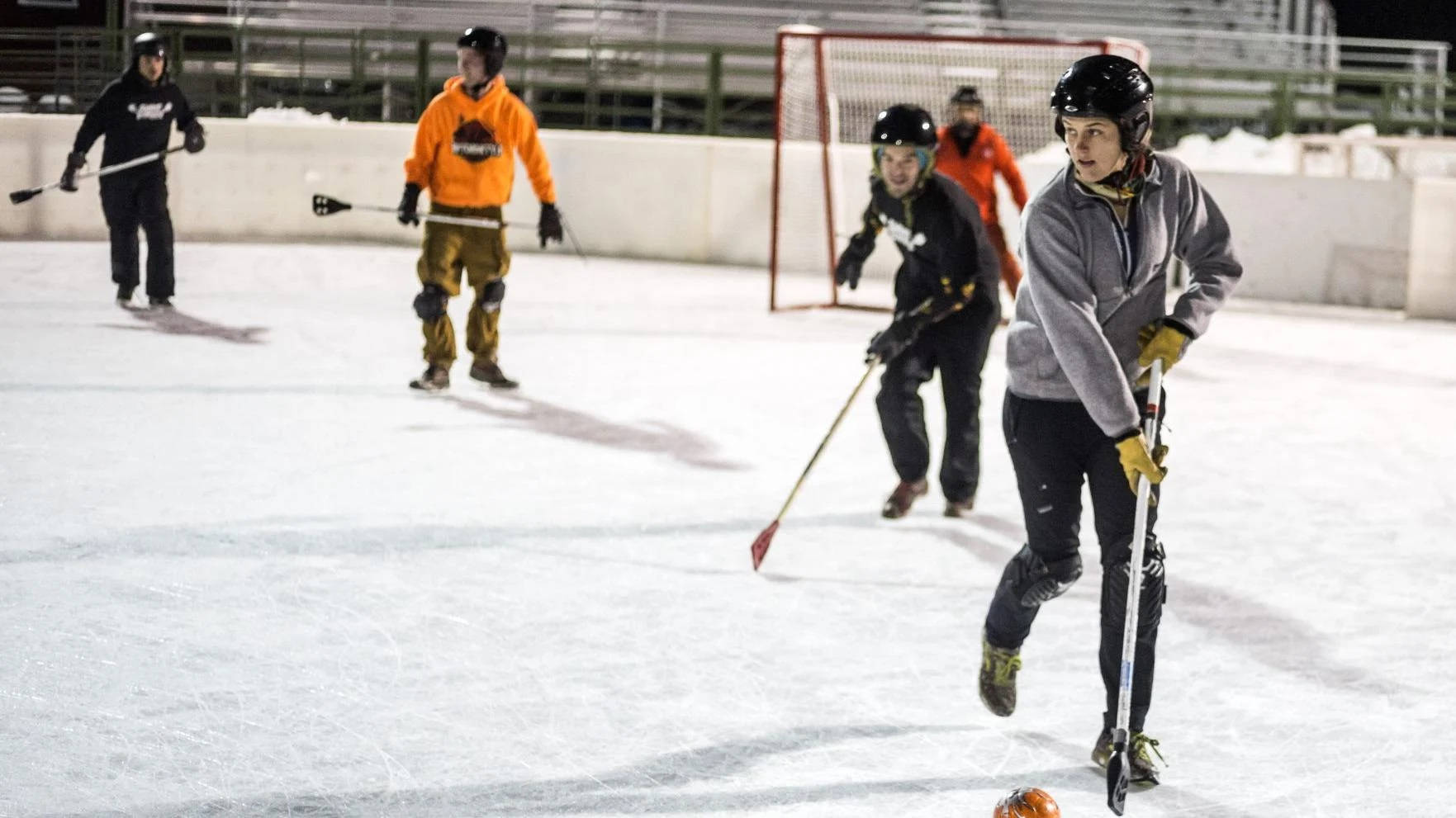 Fierce Woman Athlete In Competitive Broomball Game Background