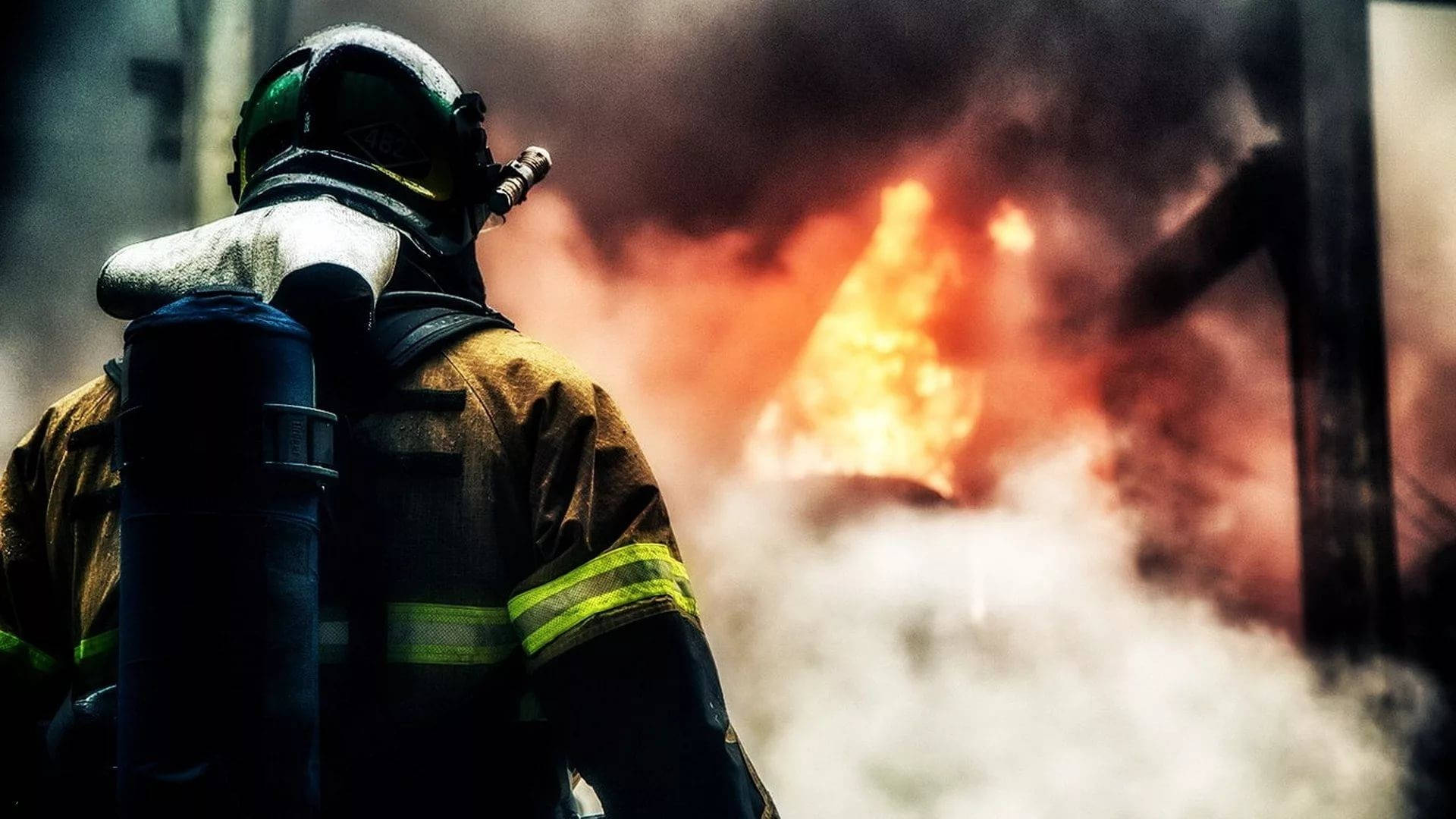 Firefighter Facing A Fiery Area Background