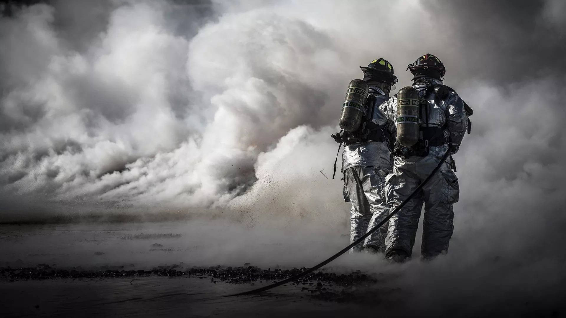 Firefighters In A Smoky Corner Background