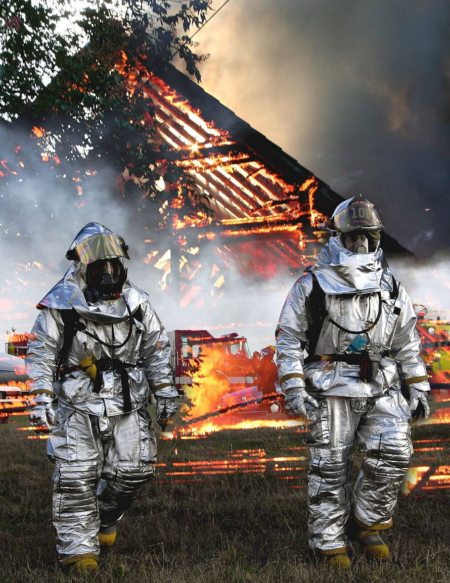 Fireman In A Silver Tunic Leaving The Burning Site Background