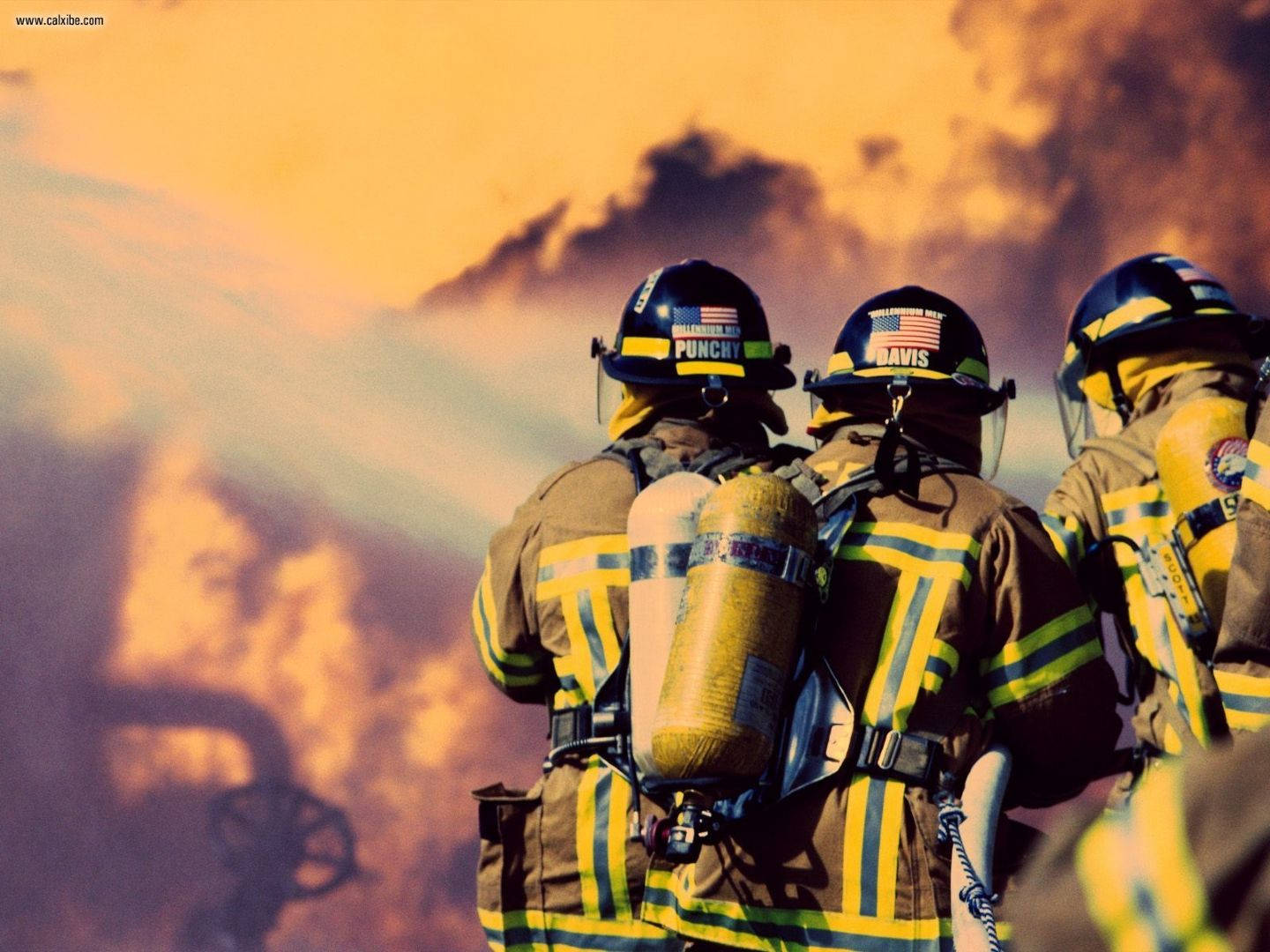 Fireman Pumping Water Into A Huge Fire Background