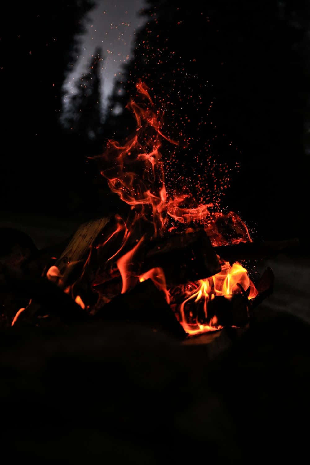 Flickering Flames Against A Blue And Black Night. Background