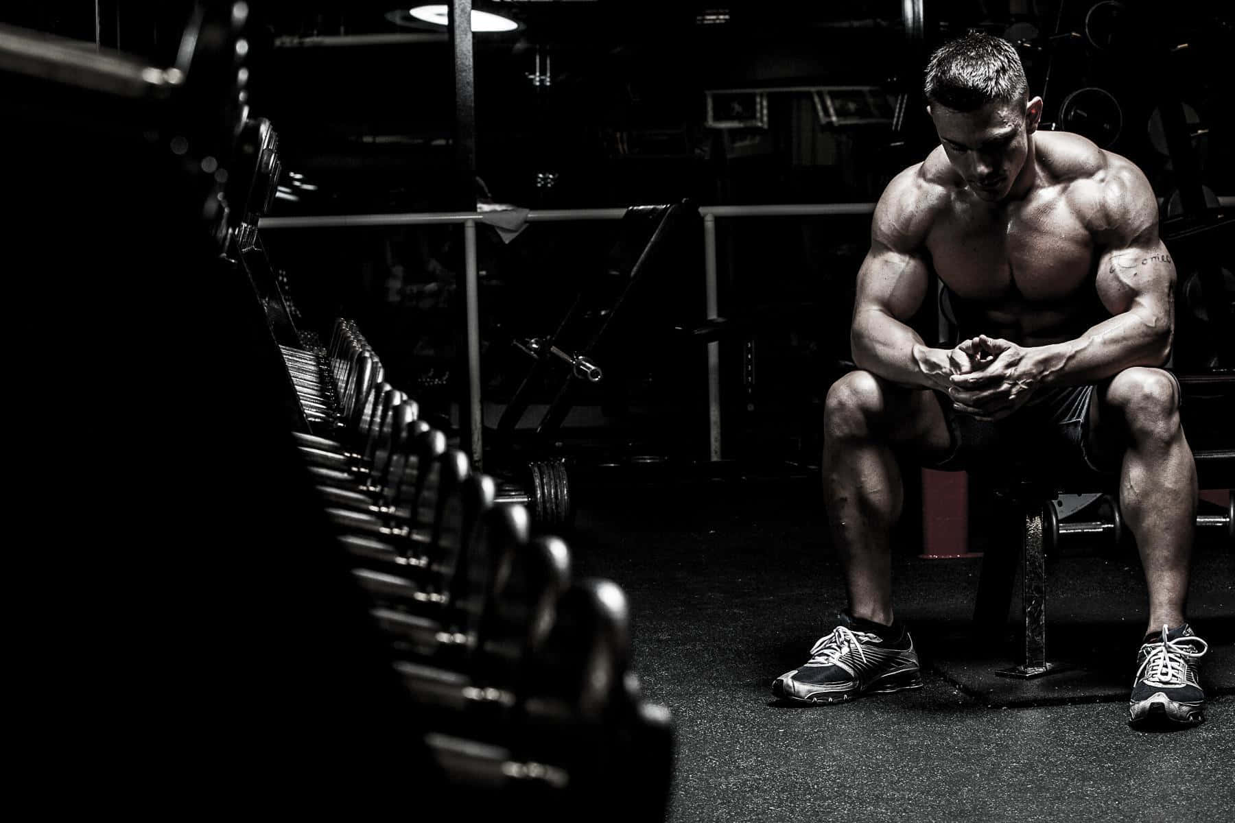 Focused Muscular Man Resting Gym Workout Background