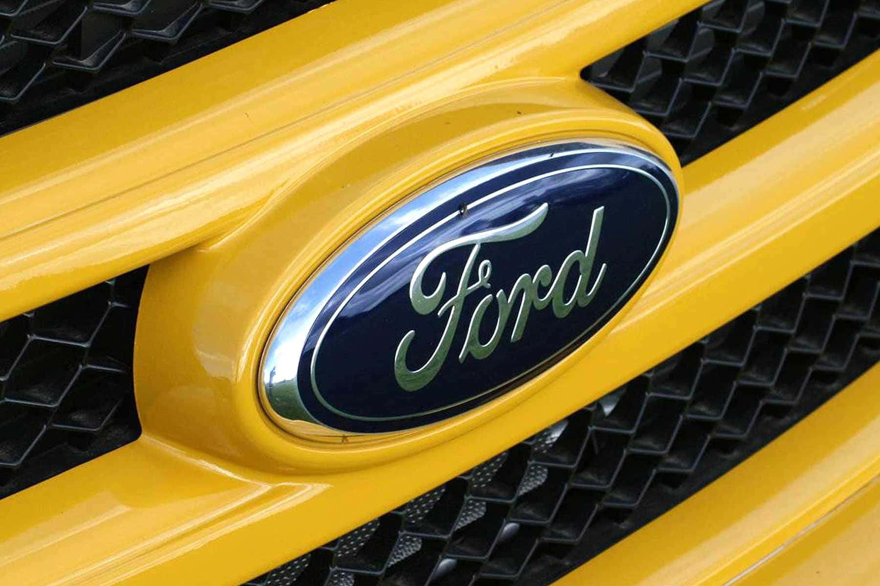 Ford's Iconic Blue Oval Logo On A Black Background Background