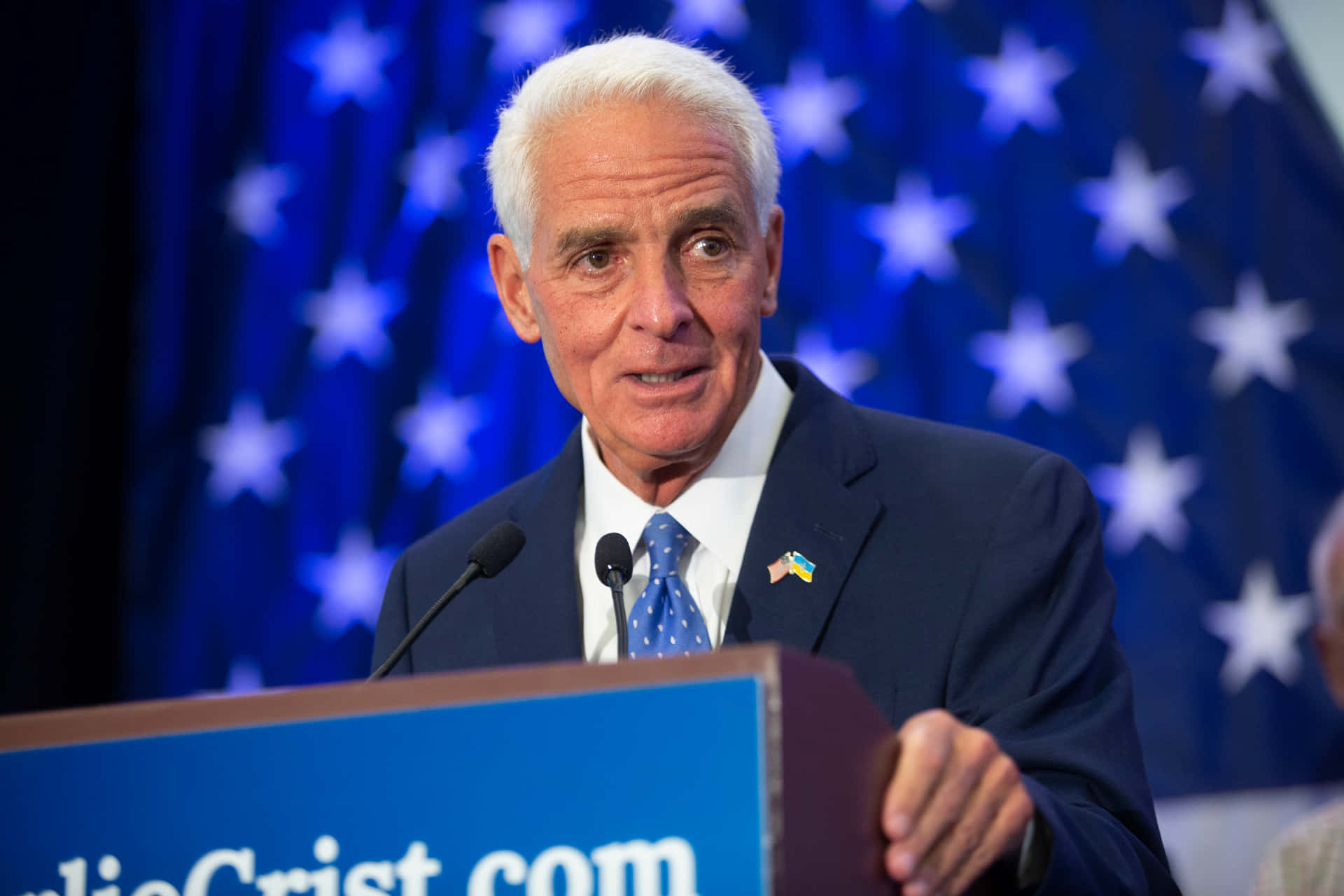 Former Florida Governor Charlie Crist Holding A Podium Background