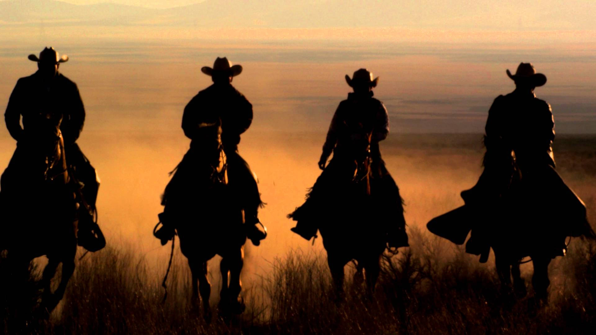 Four Cowboys Riding Horses In The Desert Background