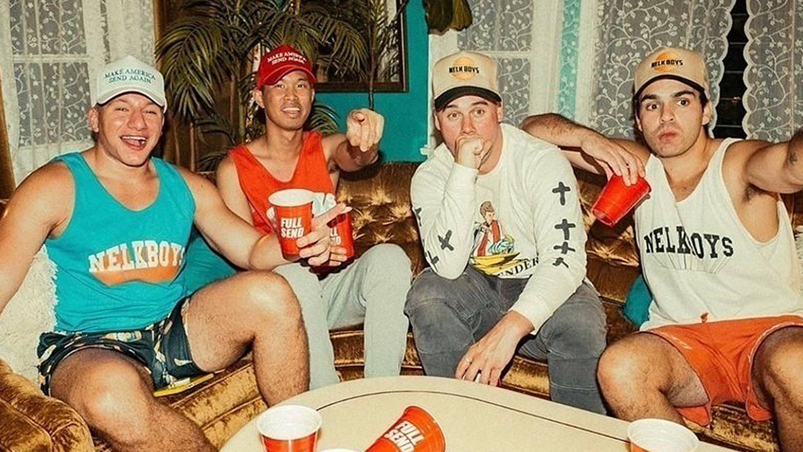 Four Men Sitting On A Couch With Drinks Background