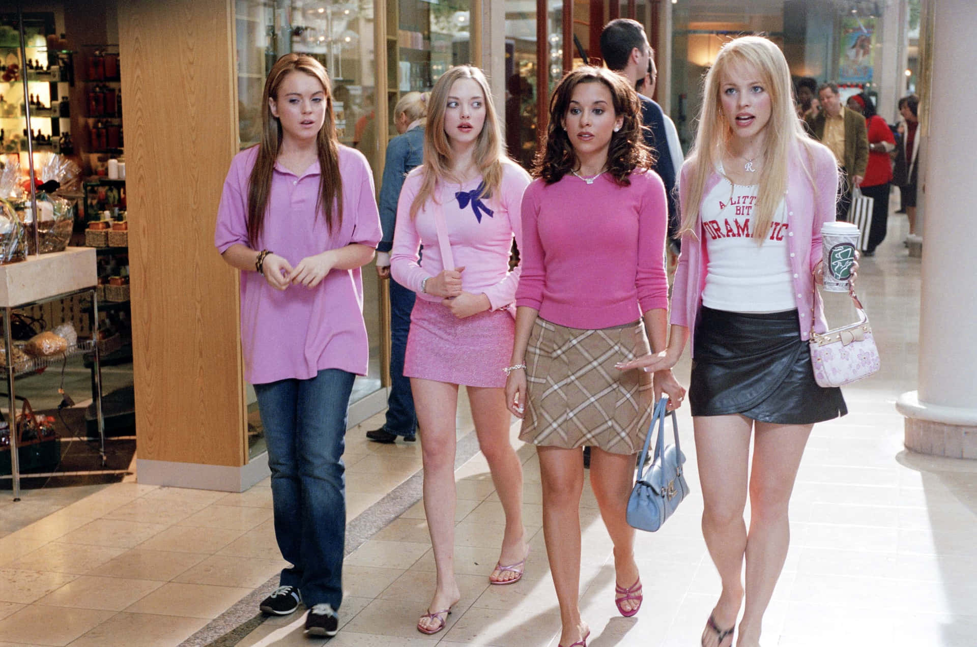 Four Young Women In Pink Walking Down A Mall Background