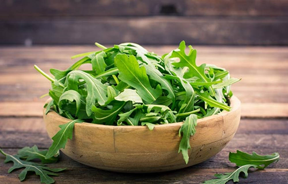 Fresh Arugula Leaves In A Wooden Bowl Background