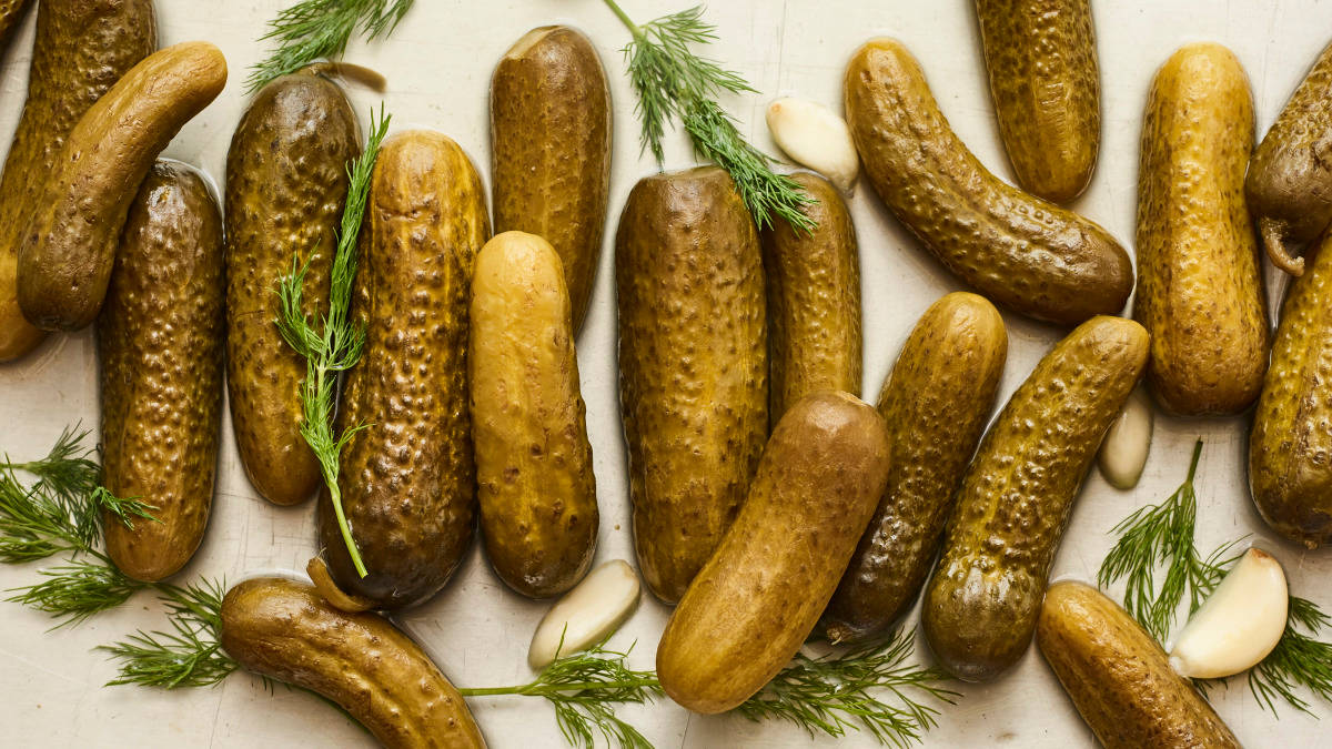 Fresh Green Pickles Immersed In Brine With Dill And Cloves Background