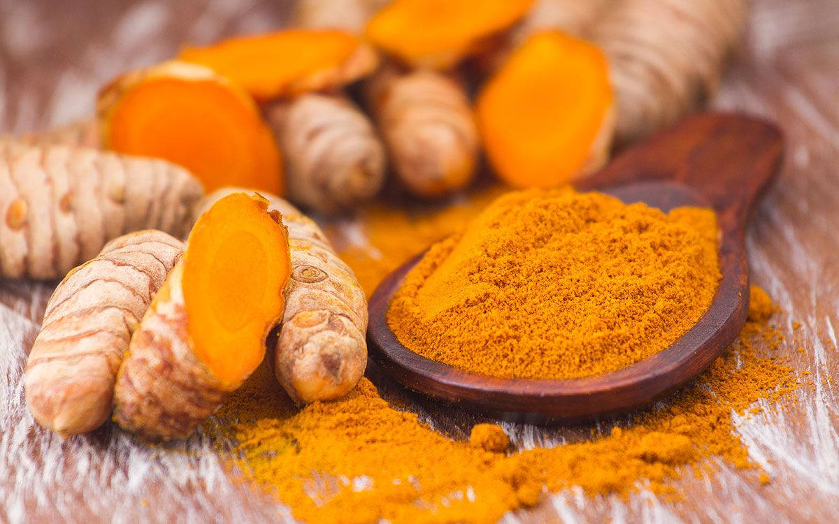 Fresh Turmeric Rhizomes Alongside Vibrant Turmeric Powder Background