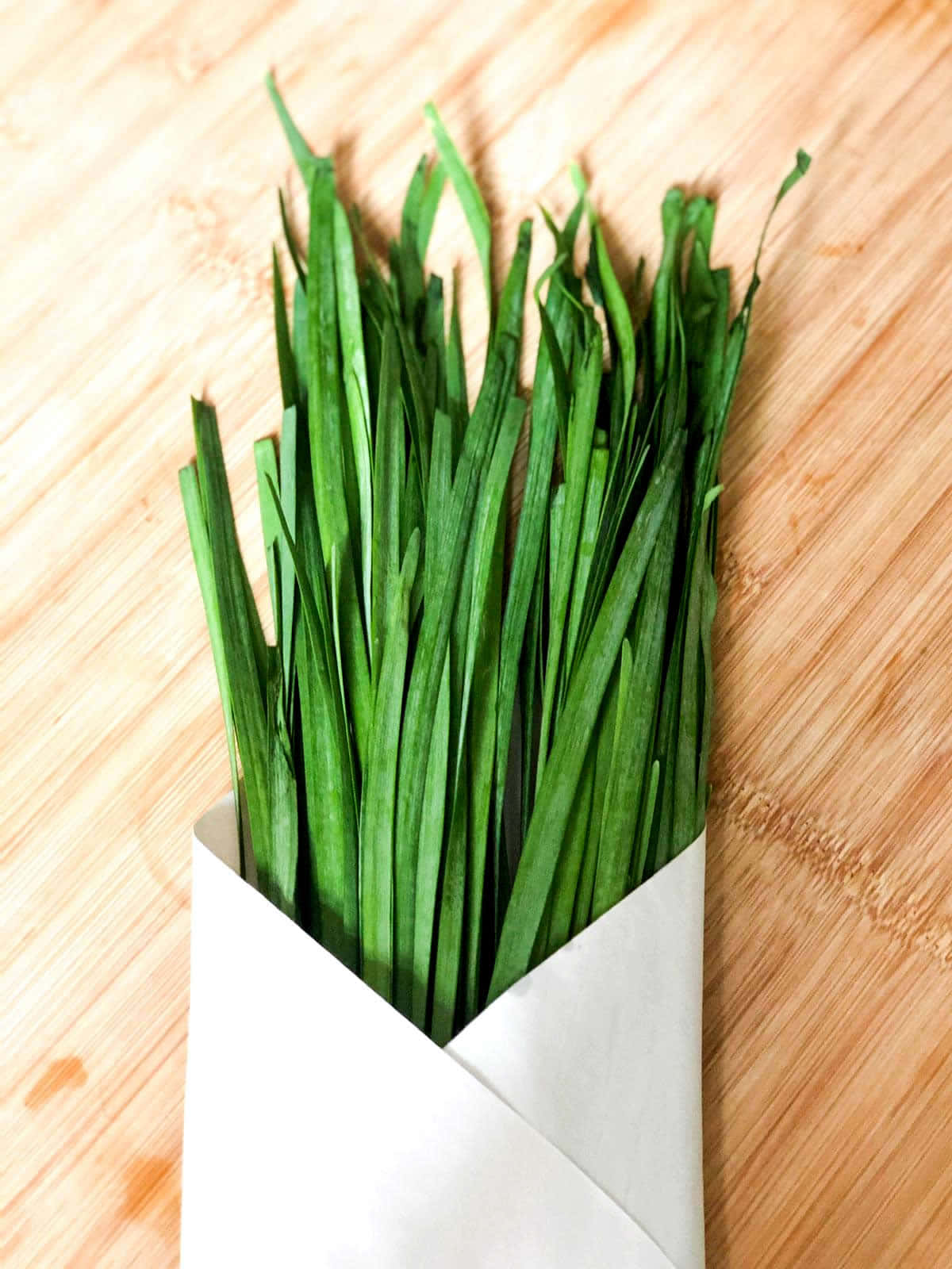 Freshly Harvested Green Chives Wrapped In White Paper Background