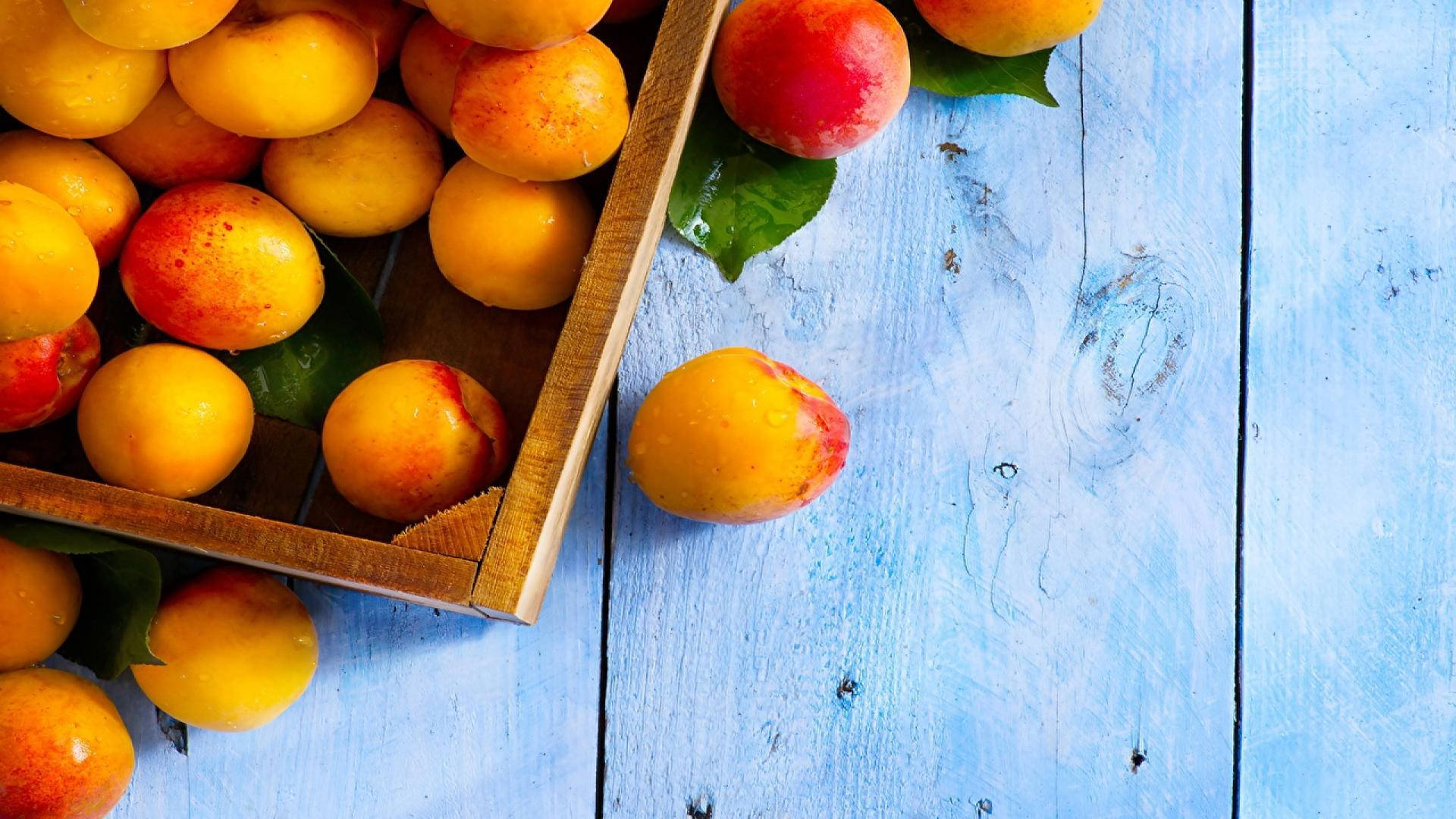 Freshly Harvested Ripe Apricots In A Box Background