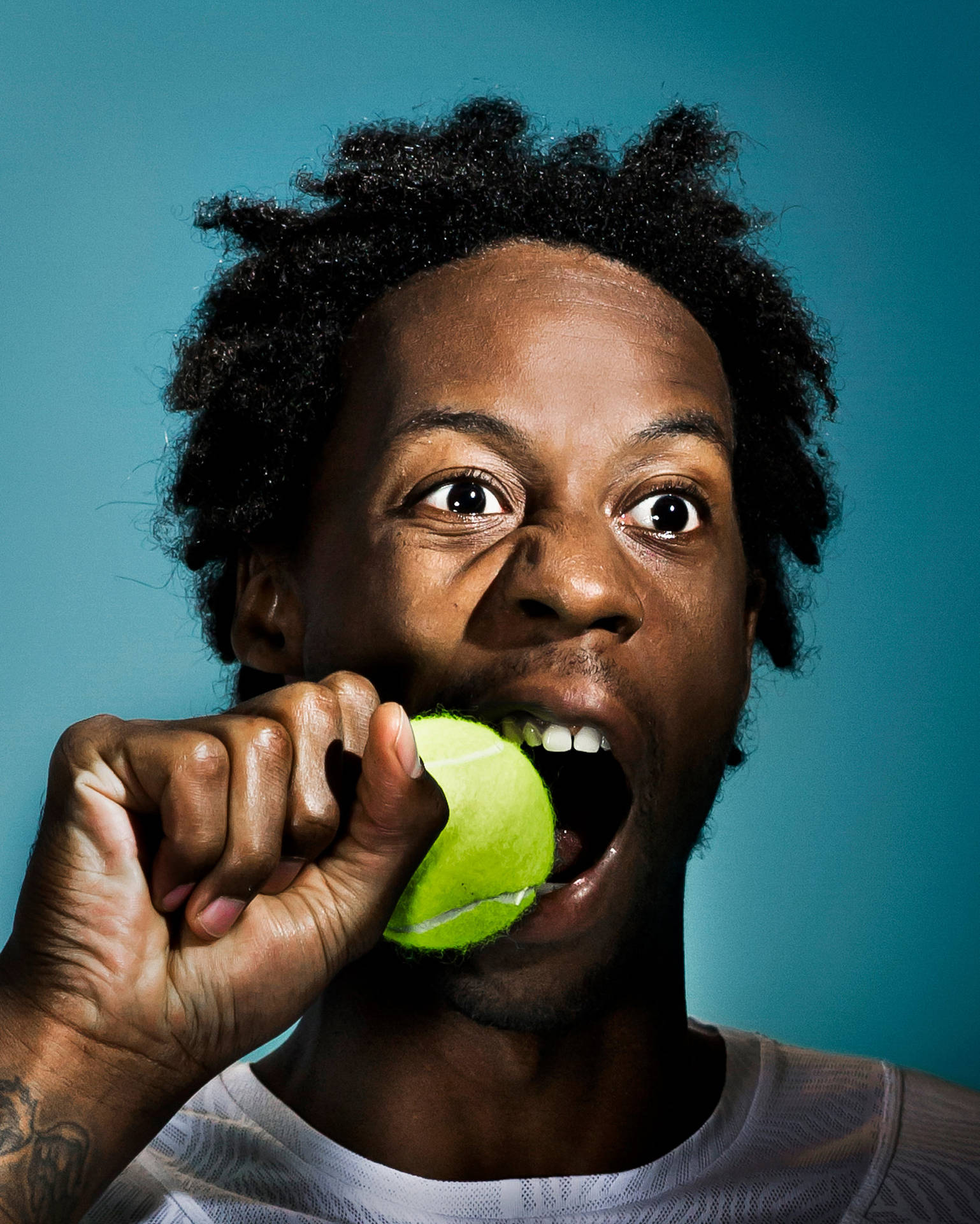 Gael Monfils Biting A Tennis Ball Background