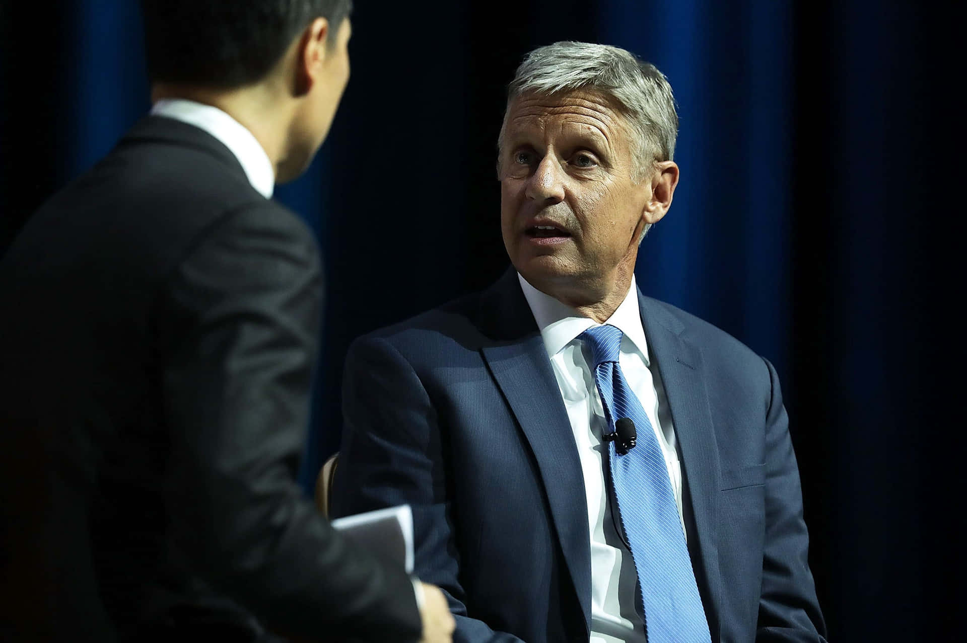 Gary Johnson Posed Against Dark Blue Curtains Background