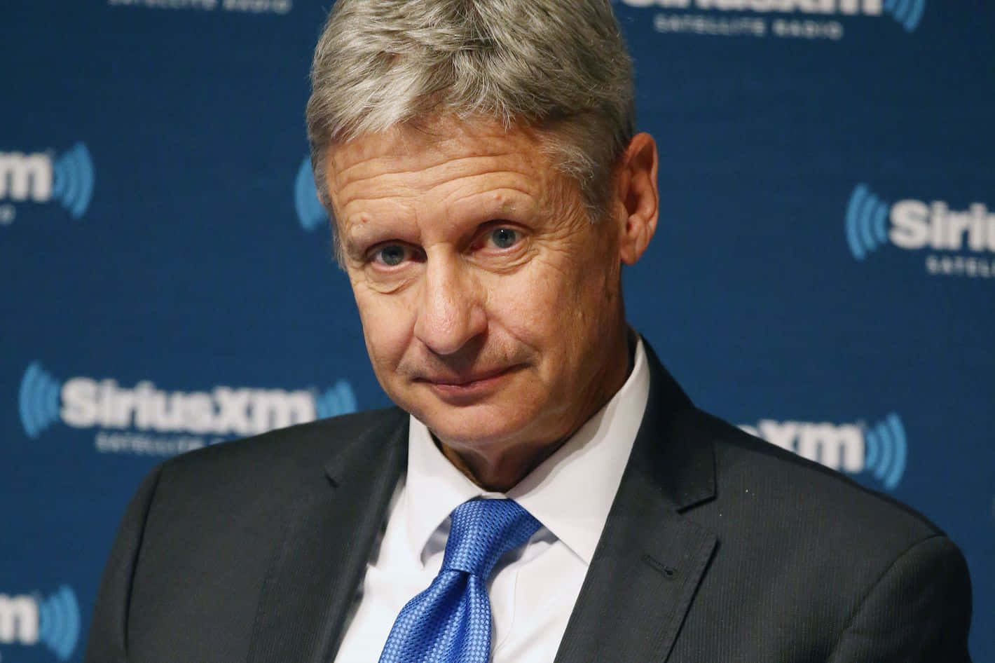 Gary Johnson Smiling And Wearing A Sophisticated Blue Tie Background