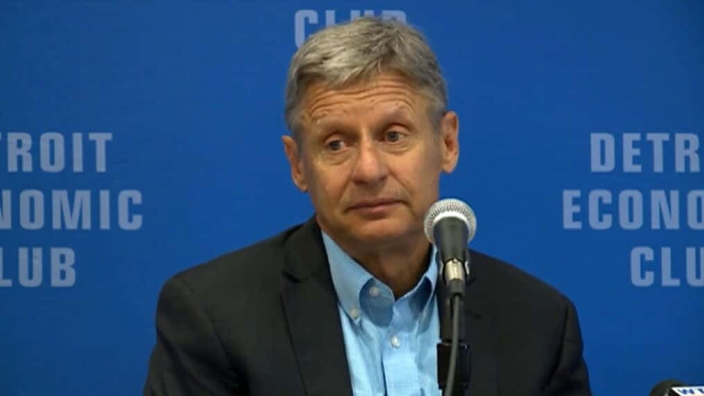 Gary Johnson With Microphone And Blue Backdrop Background