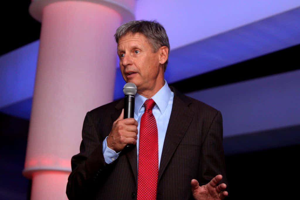 Gary Johnson With Microphone And Purple Backdrop Background